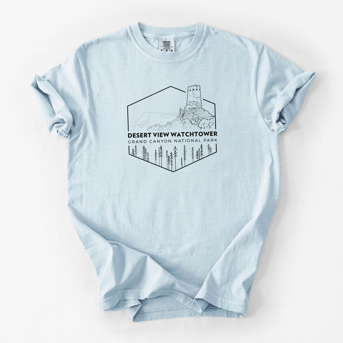 Chambray blue Comfort Colors t-shirt laid flat, printed with a black line art badge of the Desert View Watchtower above pine trees, with the words Desert View Watchtower, Grand Canyon National Park.