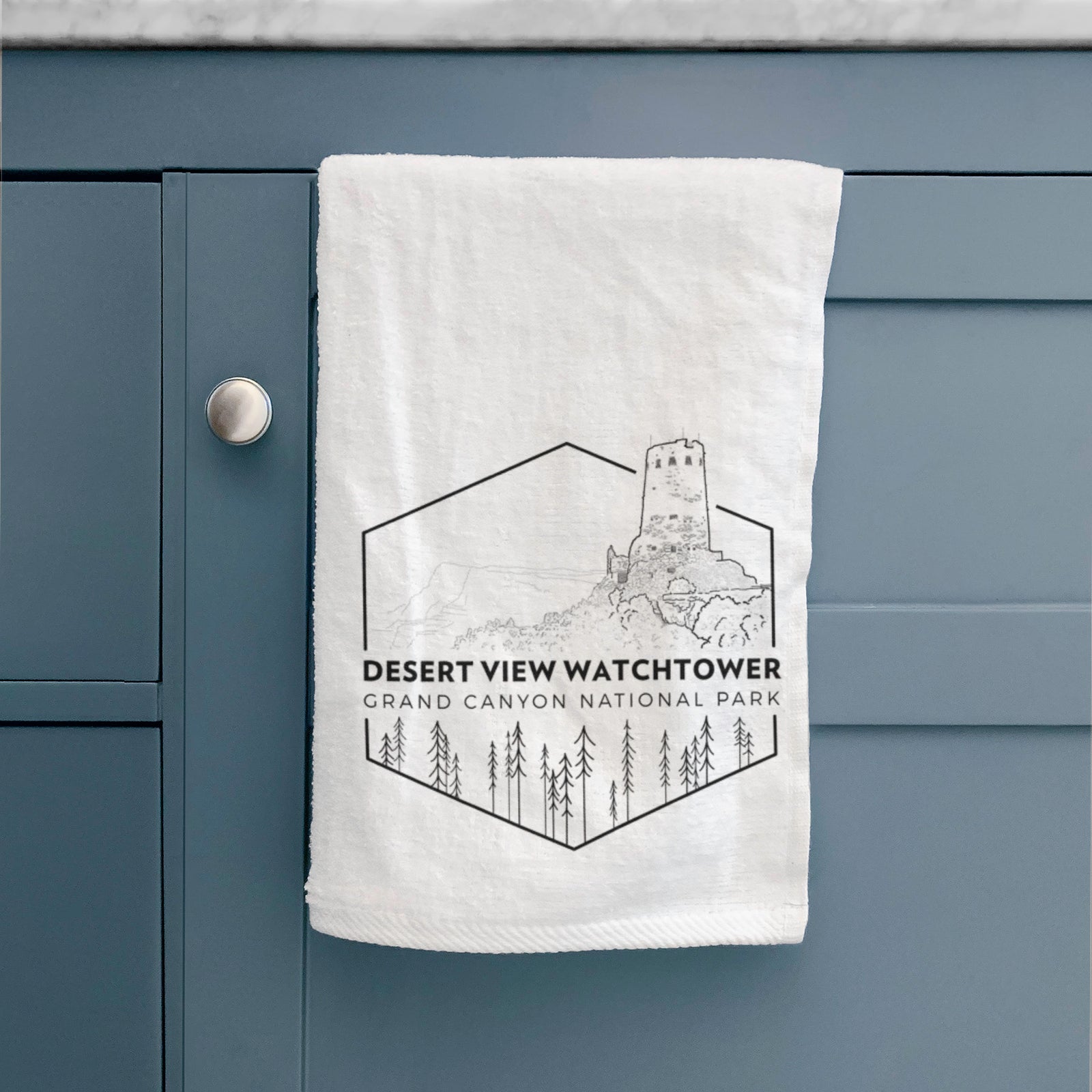 White hand towel printed with a black line art badge of the Desert View Watchtower above pine trees, with the words Desert View Watchtower, Grand Canyon National Park.