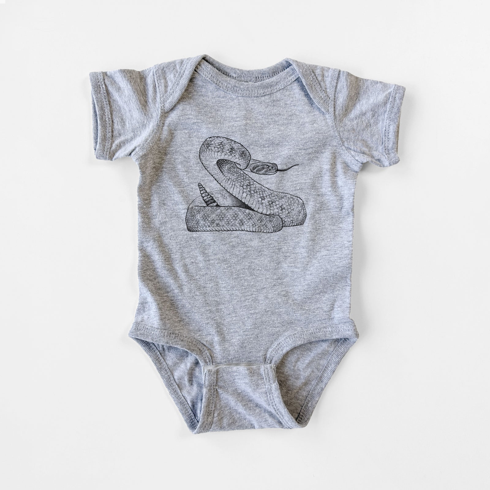 Grey baby bodysuit laid flat, printed with a detailed black ink illustration of a coiled diamondback rattlesnake.