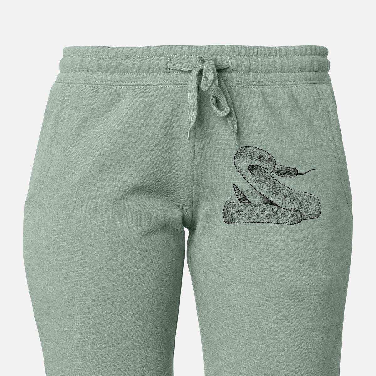 Front of sage green Cali Wave sweatpants, printed with a detailed black ink illustration of a coiled diamondback rattlesnake on the leg.