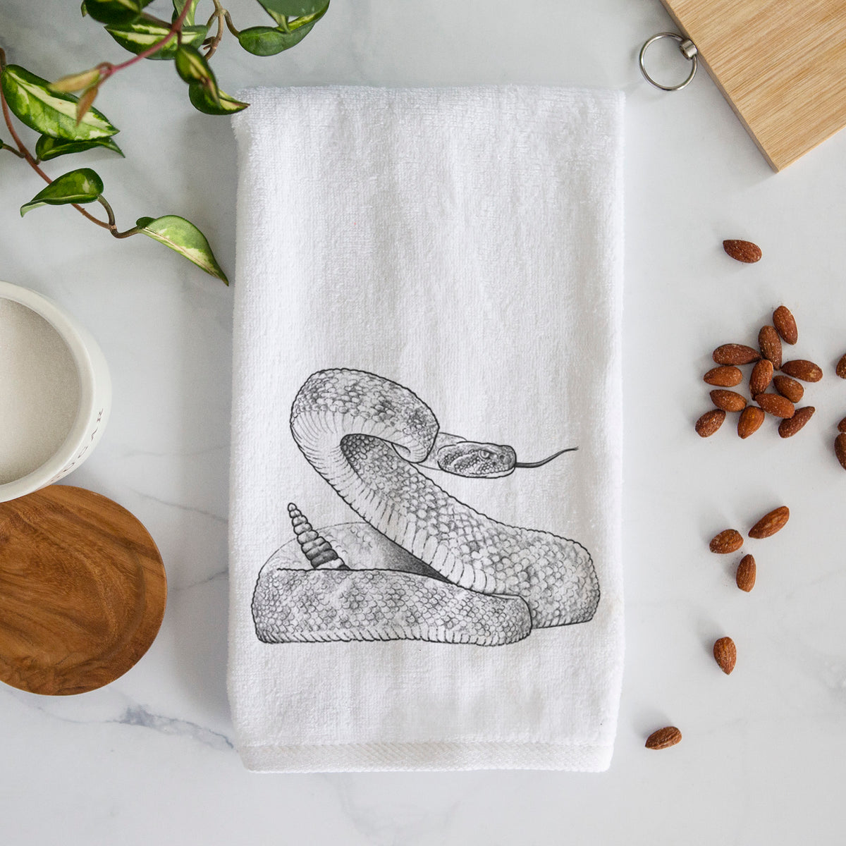 White hand towel printed with a detailed black ink illustration of a coiled diamondback rattlesnake.