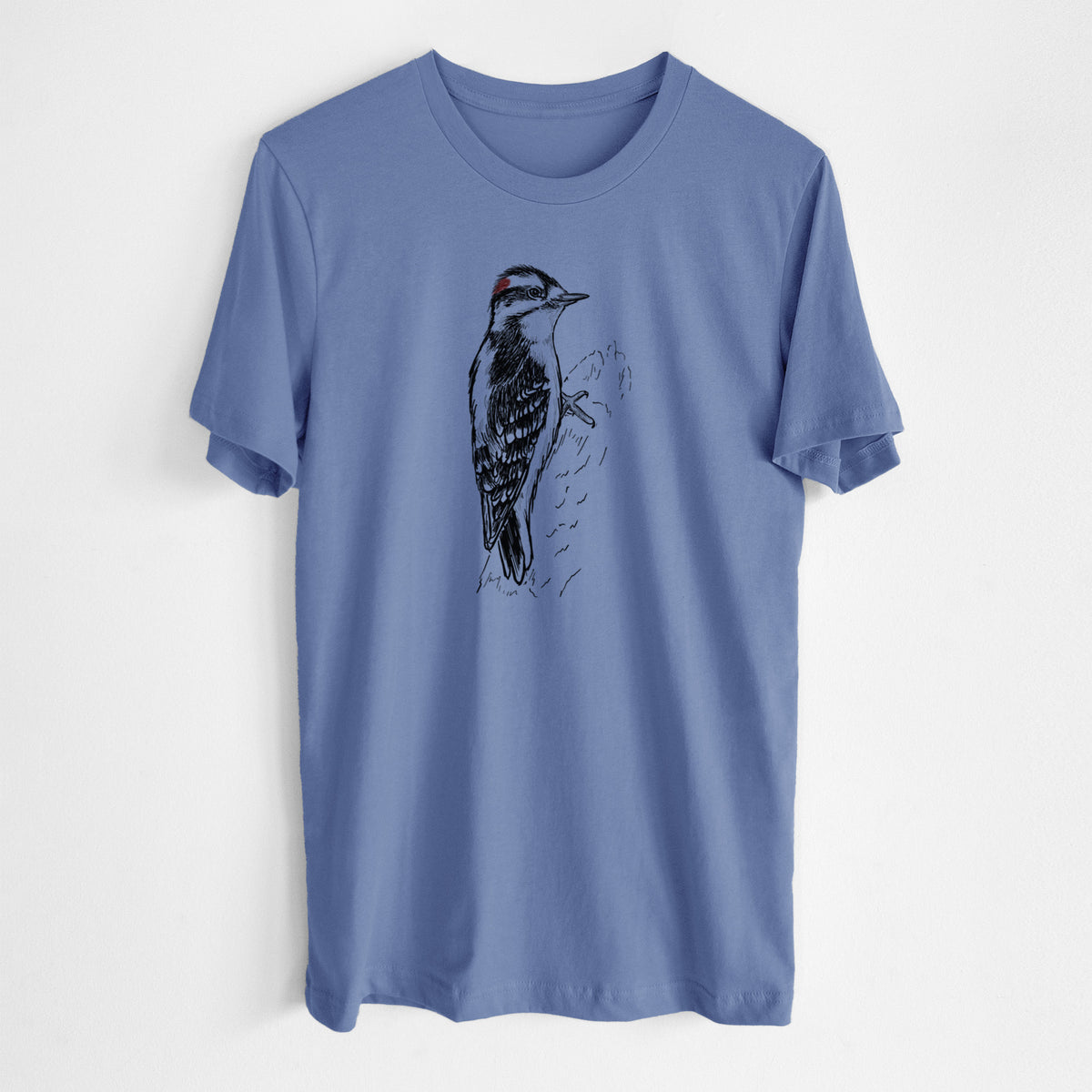 Blue bell lightweight cotton t-shirt laid flat, printed with a detailed black ink illustration of a downy woodpecker clinging to a tree trunk.