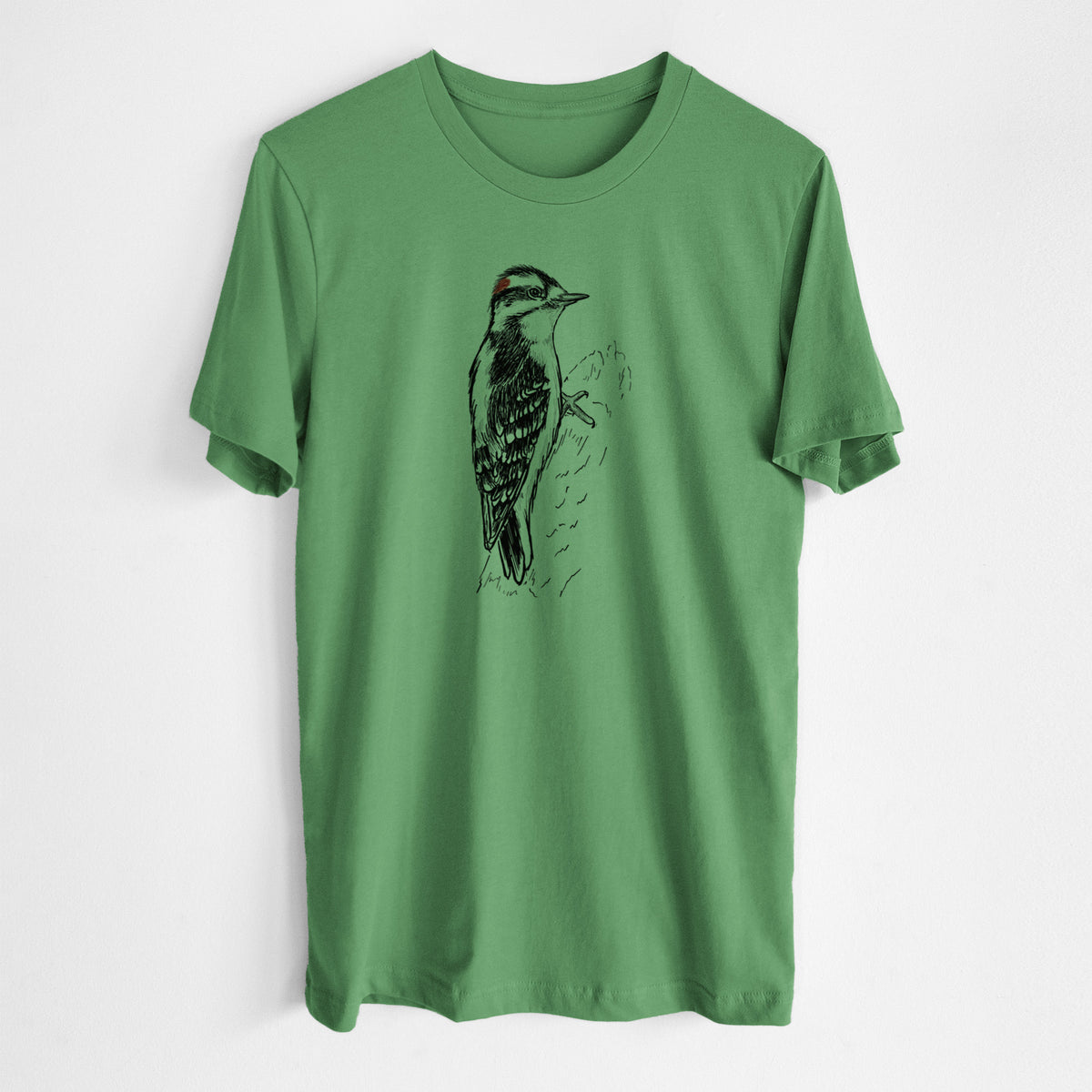 Leaf green lightweight cotton t-shirt laid flat, printed with a detailed black ink illustration of a downy woodpecker clinging to a tree trunk.