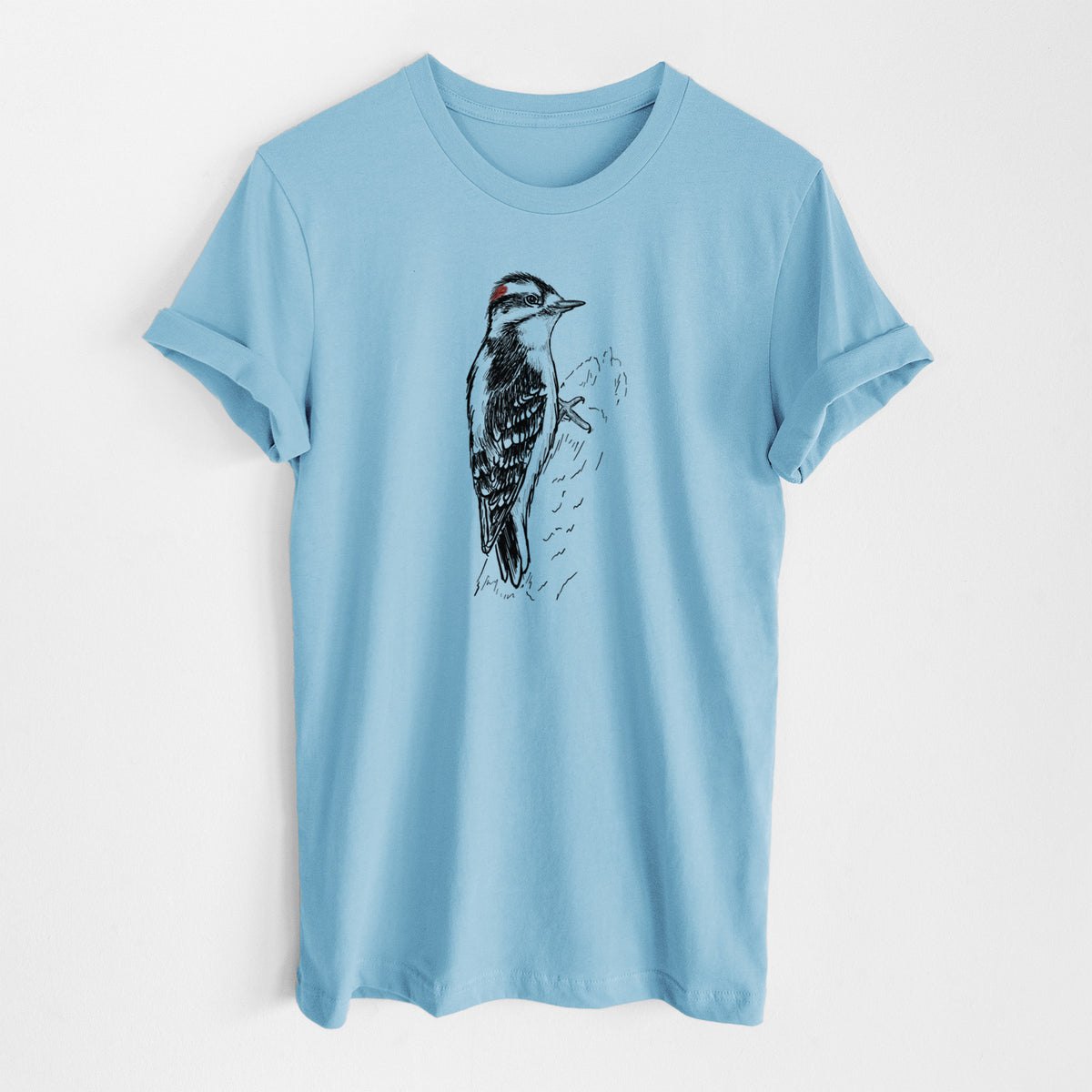 Ocean blue lightweight cotton t-shirt laid flat, printed with a detailed black ink illustration of a downy woodpecker clinging to a tree trunk.