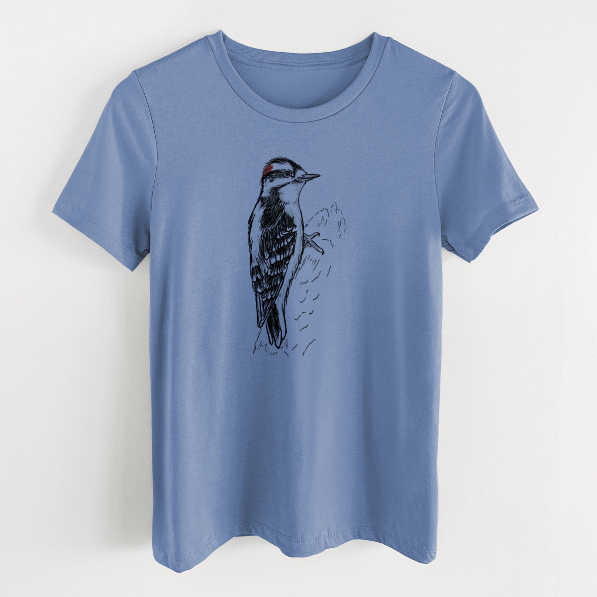 Blue bell women's relaxed fit cotton t-shirt laid flat, printed with a detailed black ink illustration of a downy woodpecker clinging to a tree trunk.