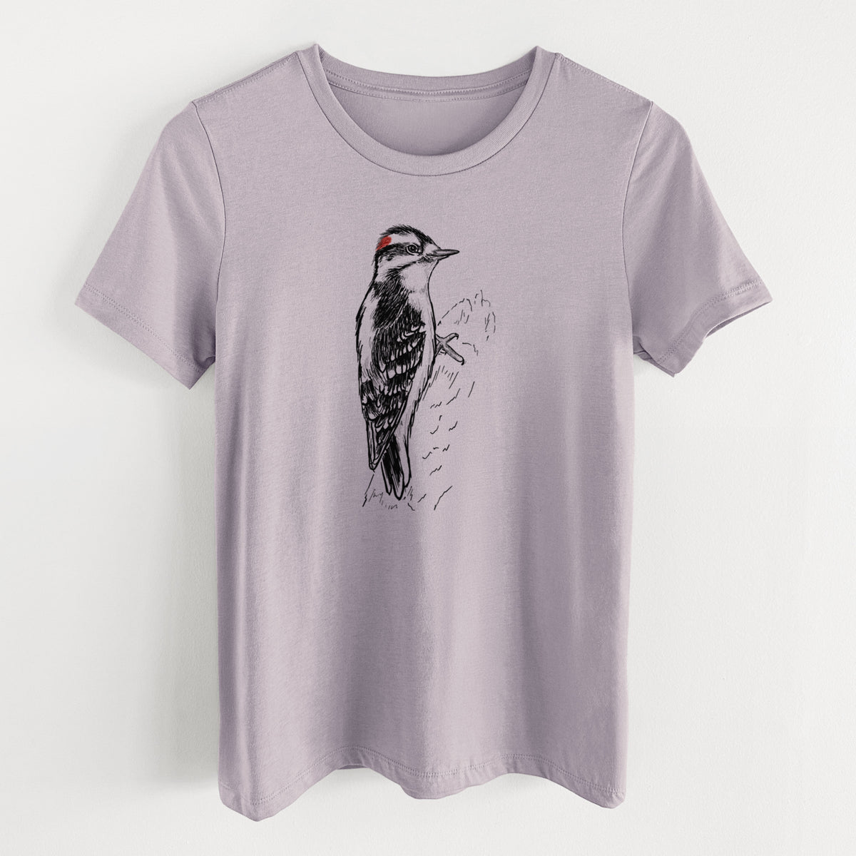 Light violet women's relaxed fit cotton t-shirt laid flat, printed with a detailed black ink illustration of a downy woodpecker clinging to a tree trunk.