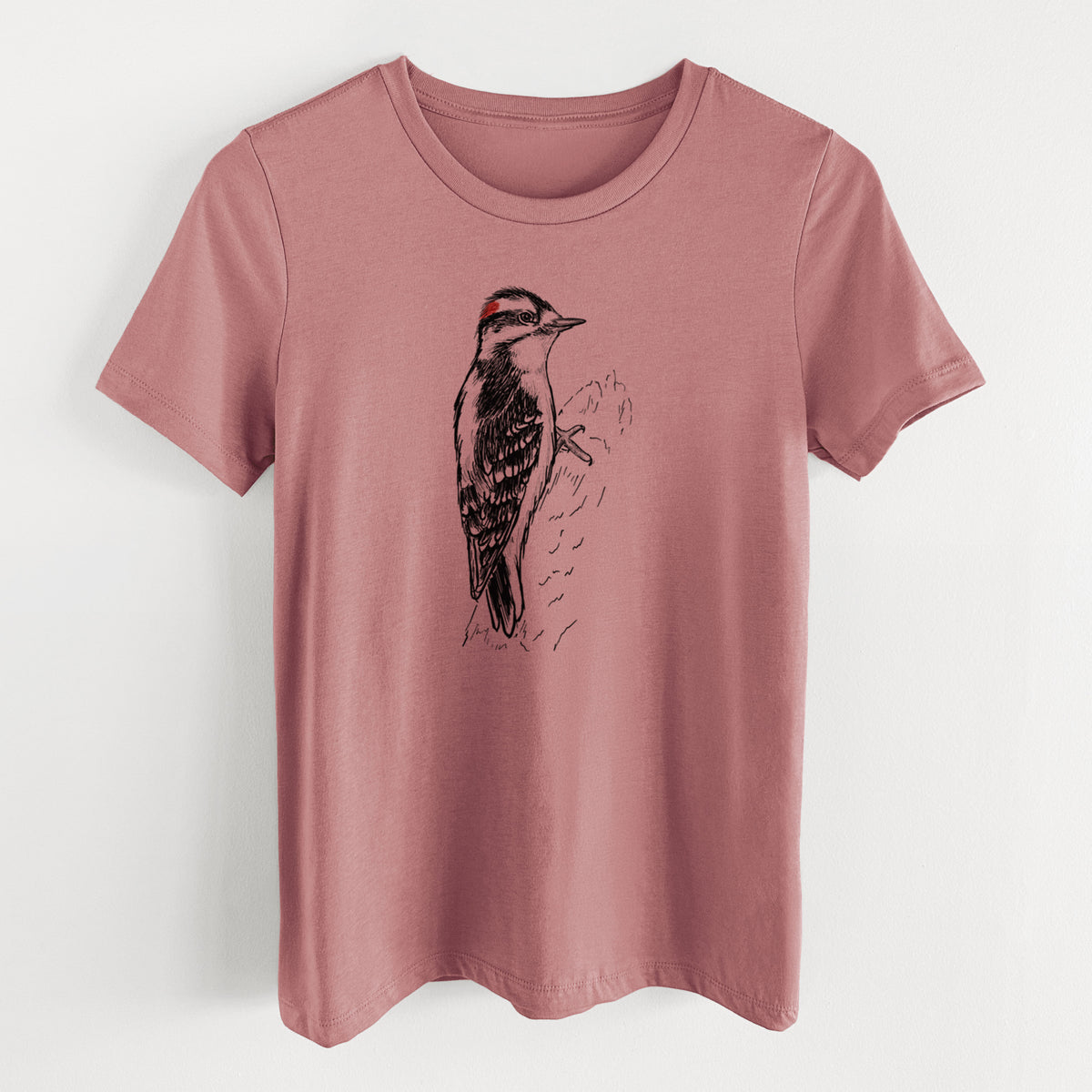 Mauve pink women's relaxed fit cotton t-shirt laid flat, printed with a detailed black ink illustration of a downy woodpecker clinging to a tree trunk.