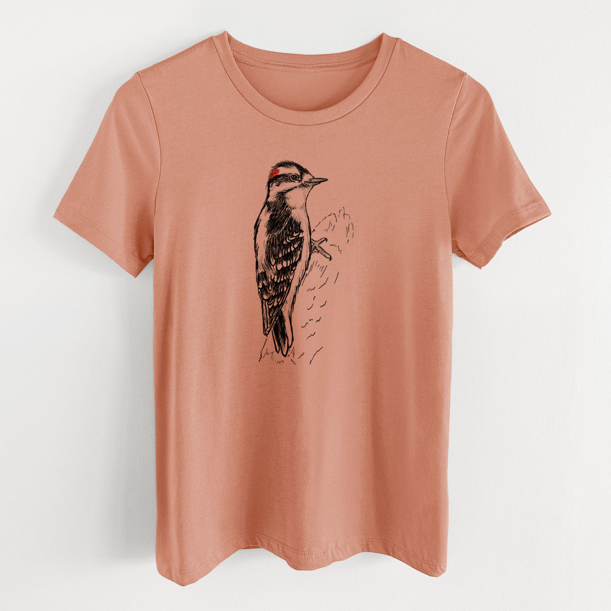 Terracotta orange women's relaxed fit cotton t-shirt laid flat, printed with a detailed black ink illustration of a downy woodpecker clinging to a tree trunk.