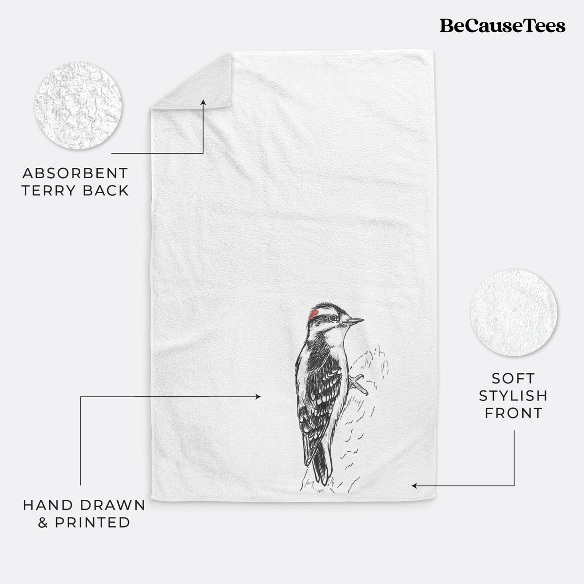 White hand towel printed with a detailed black ink illustration of a downy woodpecker clinging to a tree trunk.