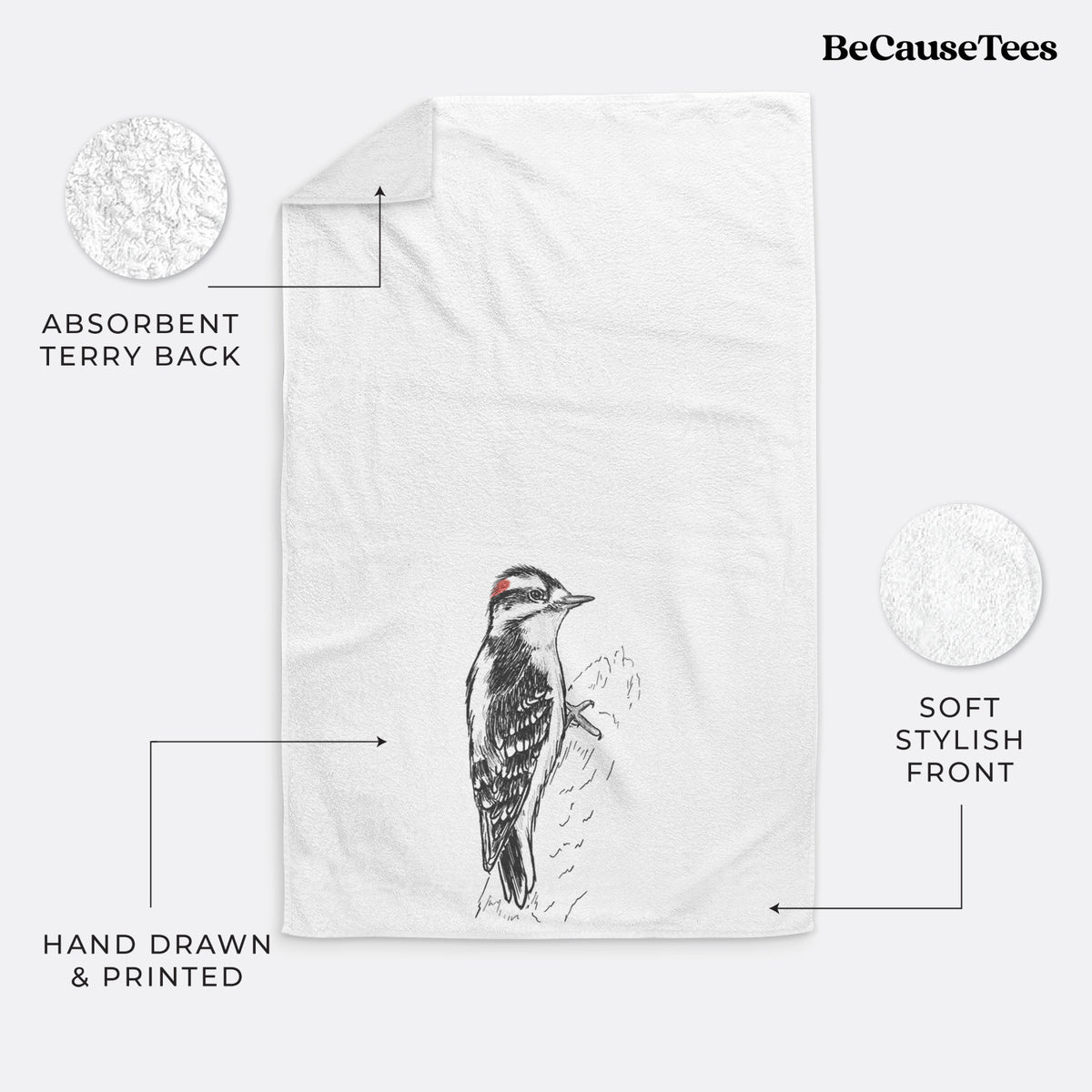 White hand towel printed with a detailed black ink illustration of a downy woodpecker clinging to a tree trunk.