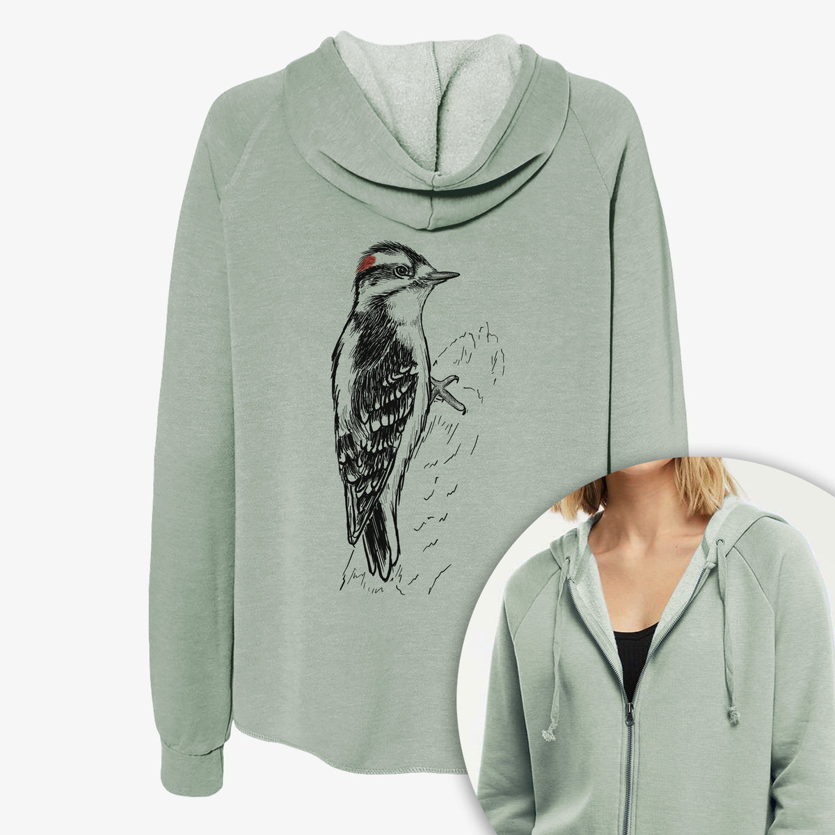 Women's Cali Wave zip-up sweatshirt printed with a detailed black ink illustration of a downy woodpecker clinging to a tree trunk, with a close-up of the zipper.