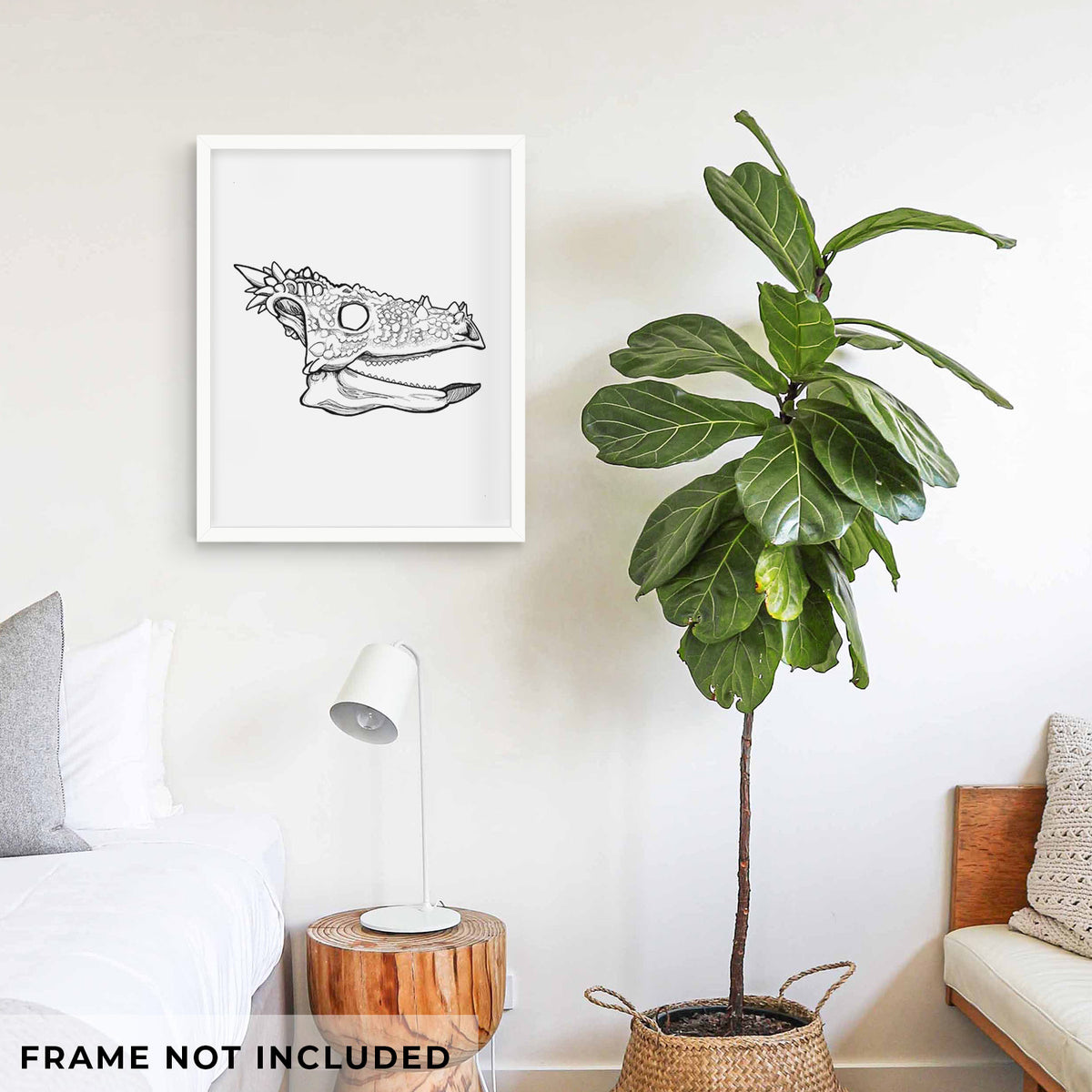 Art print of a black ink illustration of a spiky Dracorex dinosaur skull, shown framed on a living room wall beside a potted plant. Frame not included.
