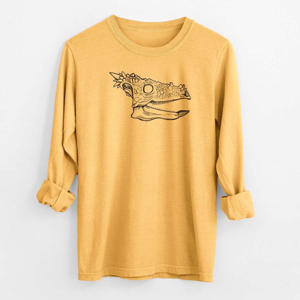 Golden wheat yellow Comfort Colors long sleeve shirt laid flat with the cuffs rolled, printed with a black ink illustration of a spiky Dracorex dinosaur skull.