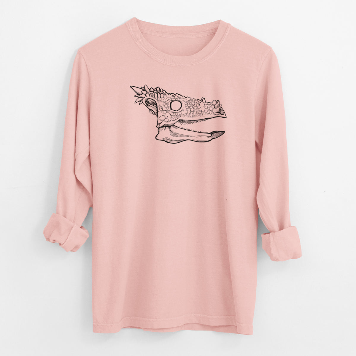 Peachy Comfort Colors long sleeve shirt laid flat with the cuffs rolled, printed with a black ink illustration of a spiky Dracorex dinosaur skull.