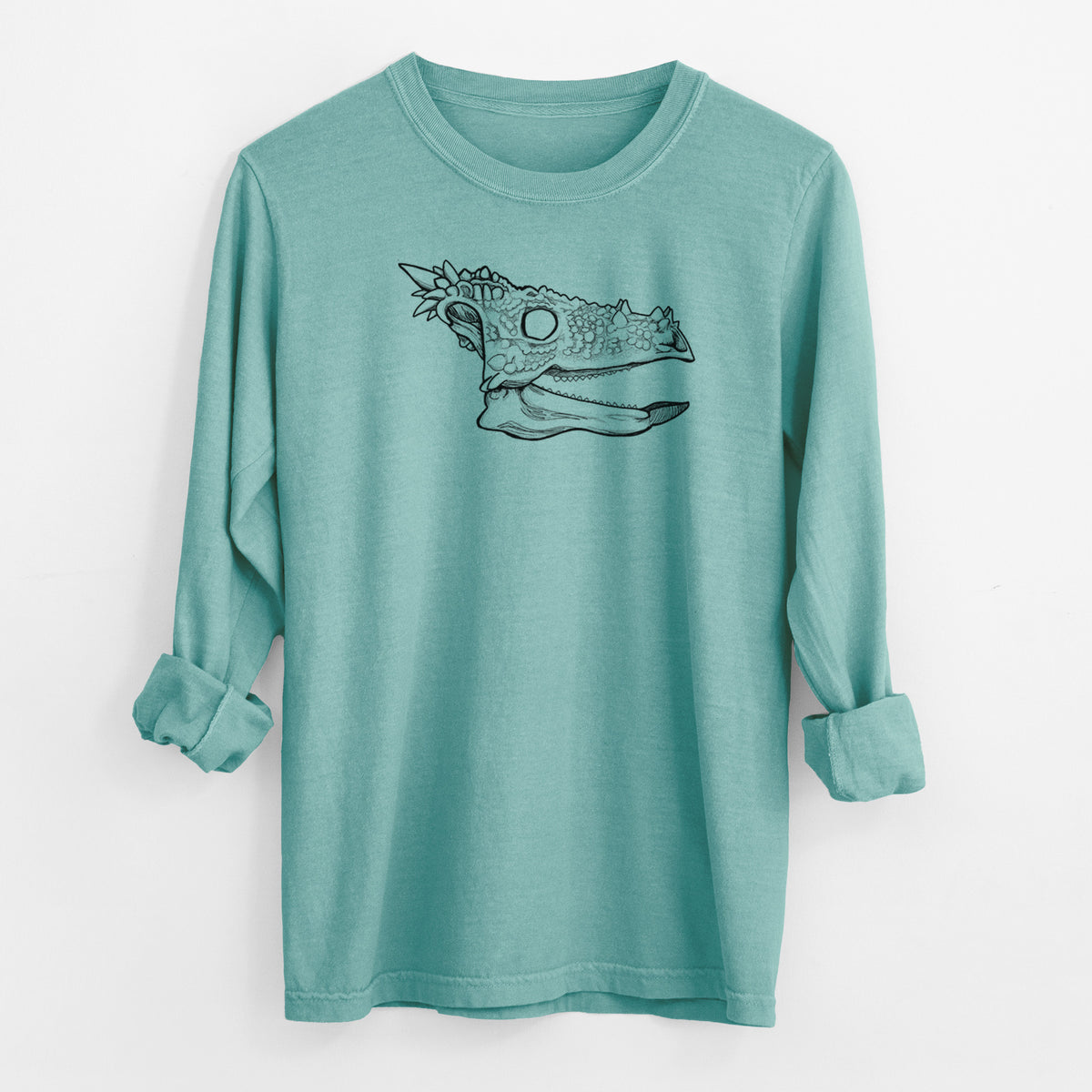 Reef green Comfort Colors long sleeve shirt laid flat with the cuffs rolled, printed with a black ink illustration of a spiky Dracorex dinosaur skull.