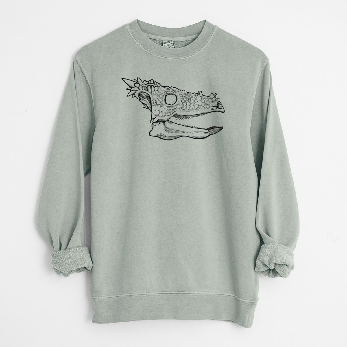 Sage green pigment dyed crewneck sweatshirt laid flat with the sleeves rolled, printed with a black ink illustration of a spiky Dracorex dinosaur skull.