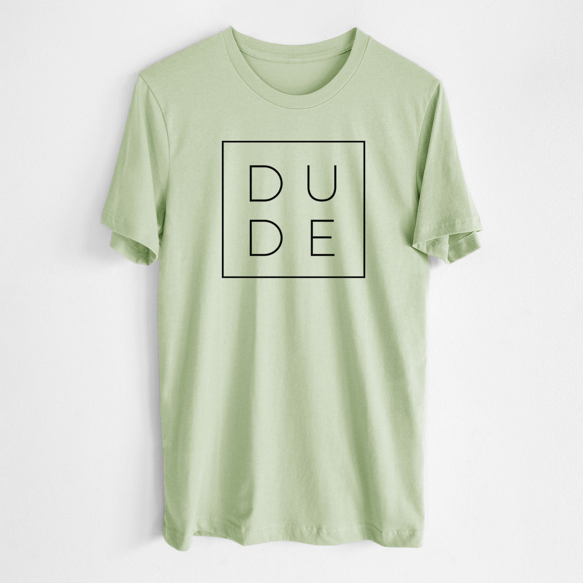 Spring green lightweight cotton t-shirt laid flat, printed with the word DUDE in thin black letters stacked inside a square outline.