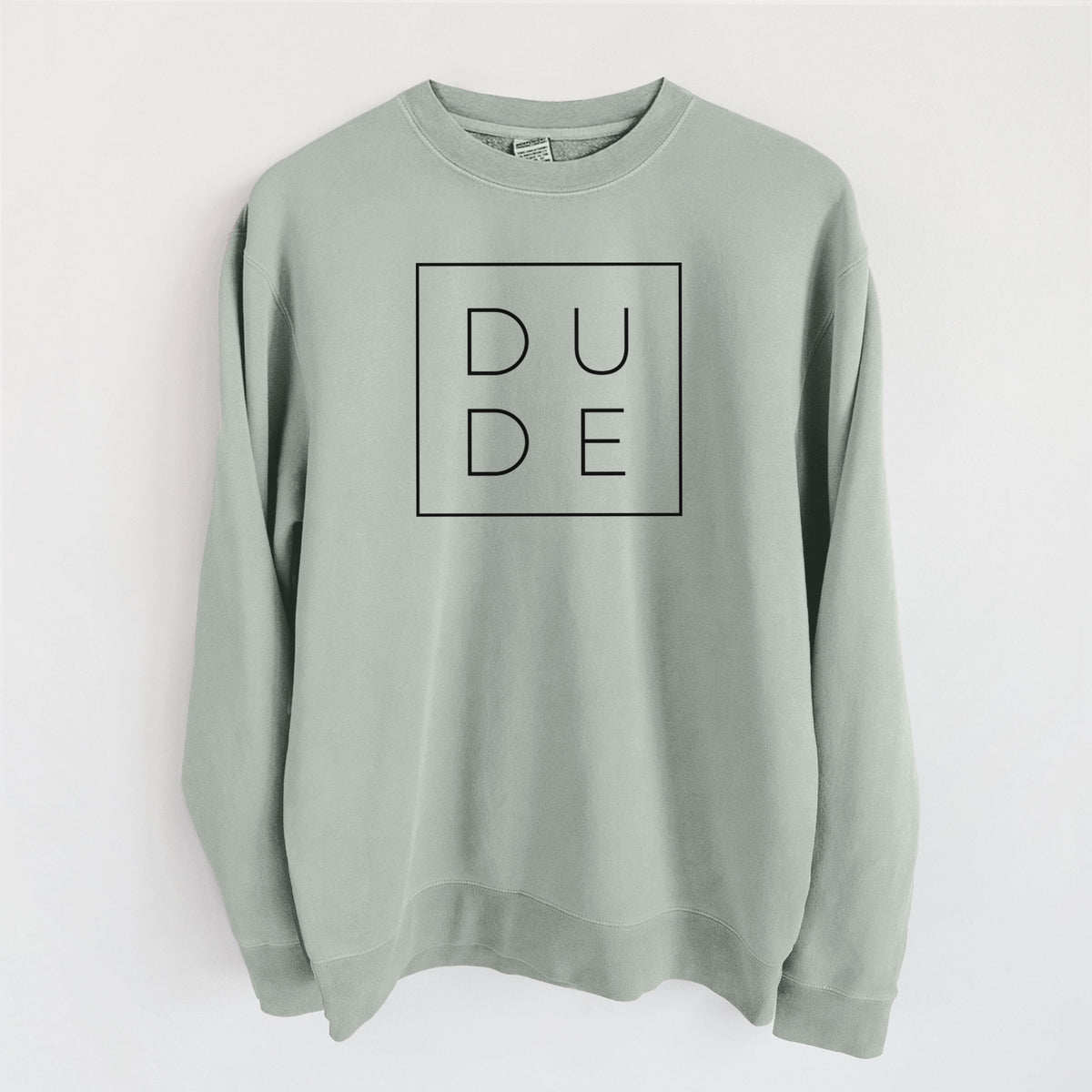 Sage green pigment dyed crewneck sweatshirt laid flat, printed with the word DUDE in thin black letters stacked inside a square outline.