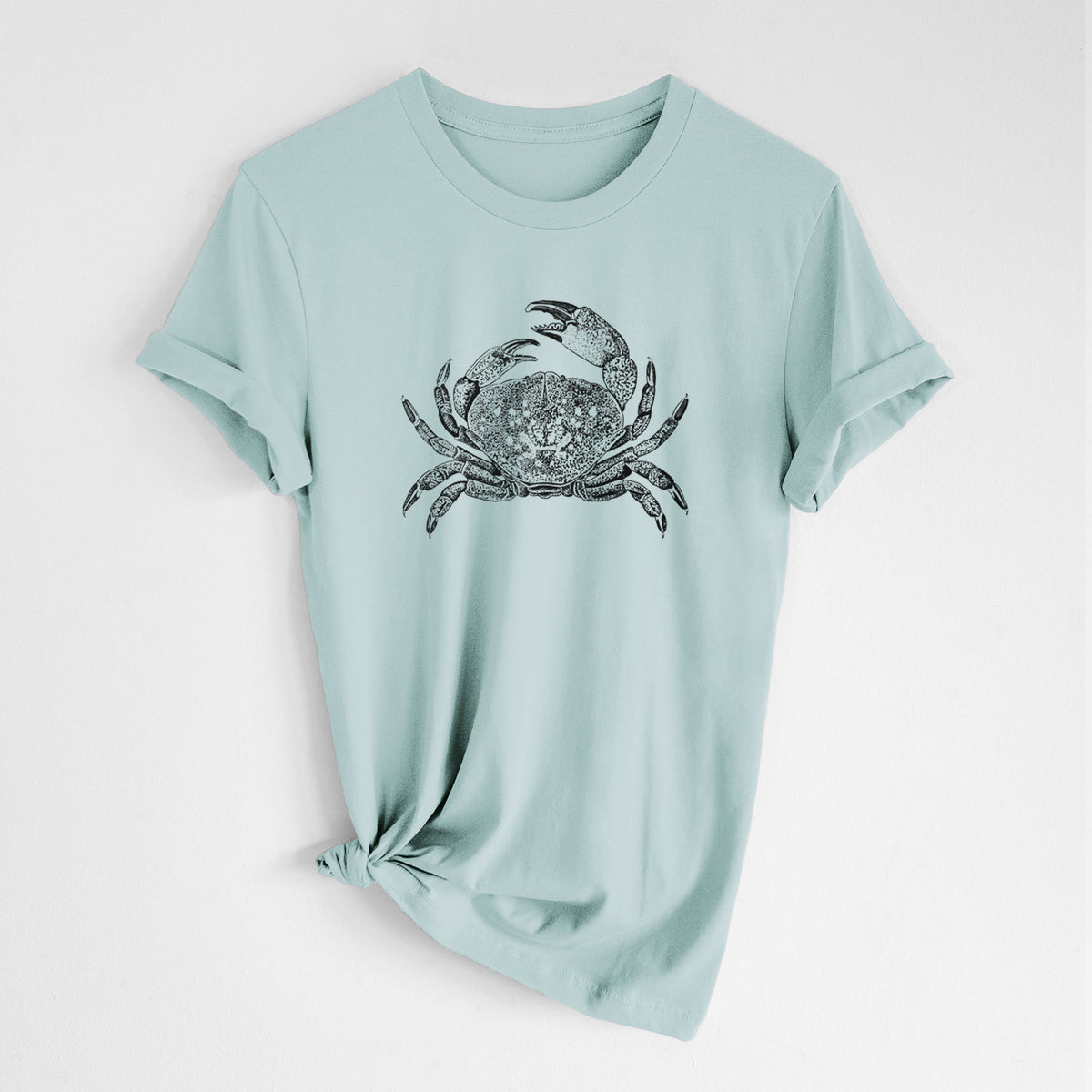 Dusty blue lightweight cotton t-shirt laid flat with the sleeves rolled, printed with a detailed black ink illustration of a Dungeness crab with claws raised, seen from above.