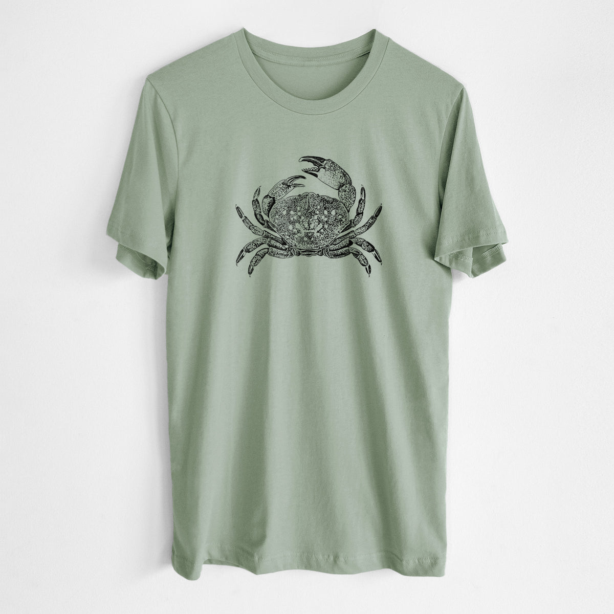 Sage green lightweight cotton t-shirt laid flat, printed with a detailed black ink illustration of a Dungeness crab with claws raised, seen from above.