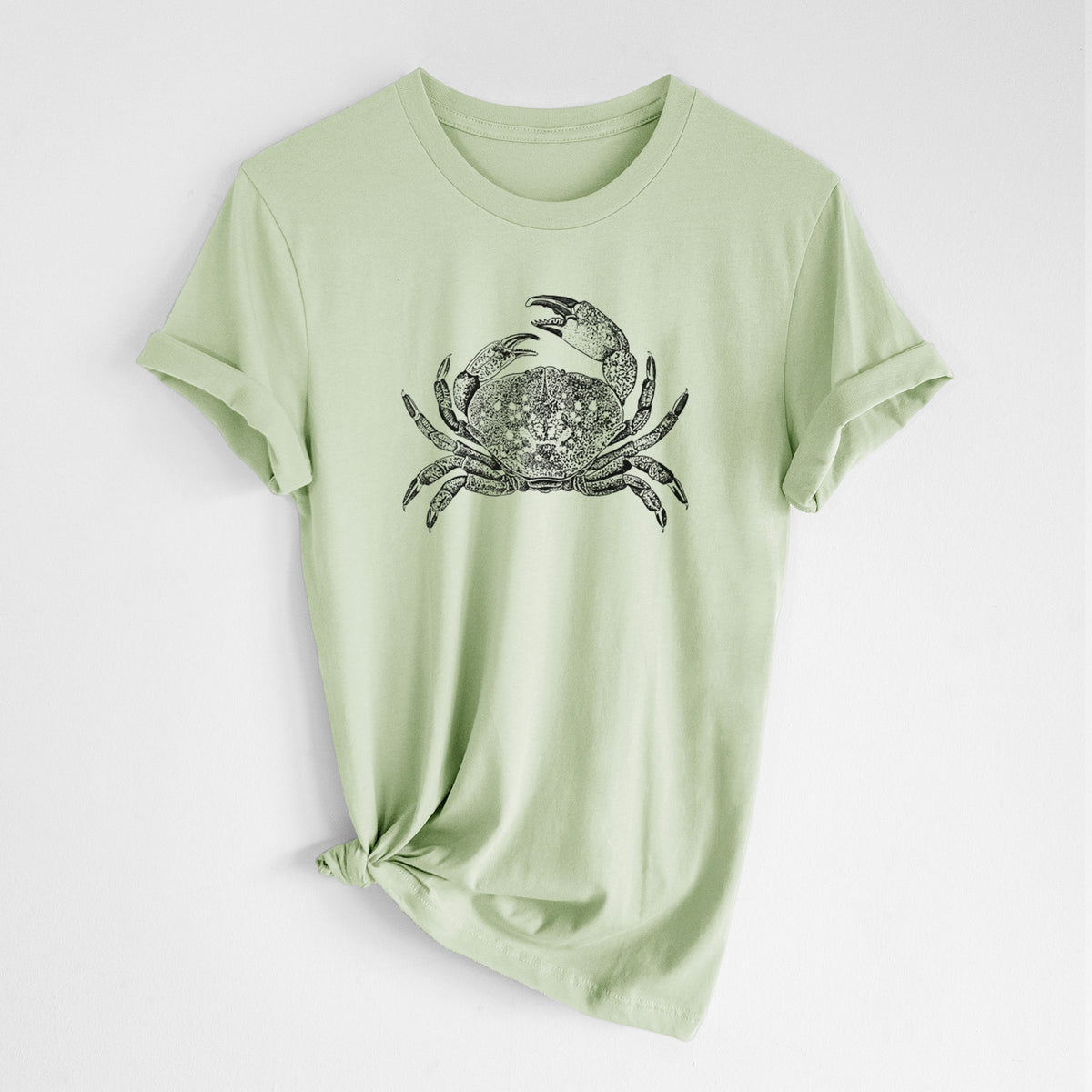 Spring green lightweight cotton t-shirt laid flat with the sleeves rolled, printed with a detailed black ink illustration of a Dungeness crab with claws raised, seen from above.