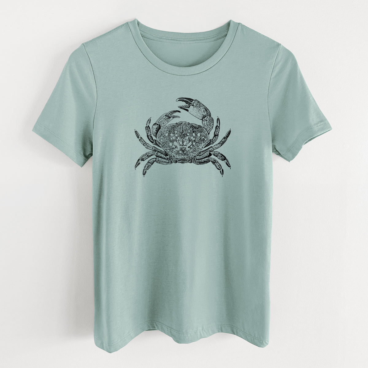 Dusty blue women's relaxed fit cotton t-shirt laid flat, printed with a detailed black ink illustration of a Dungeness crab with claws raised, seen from above.