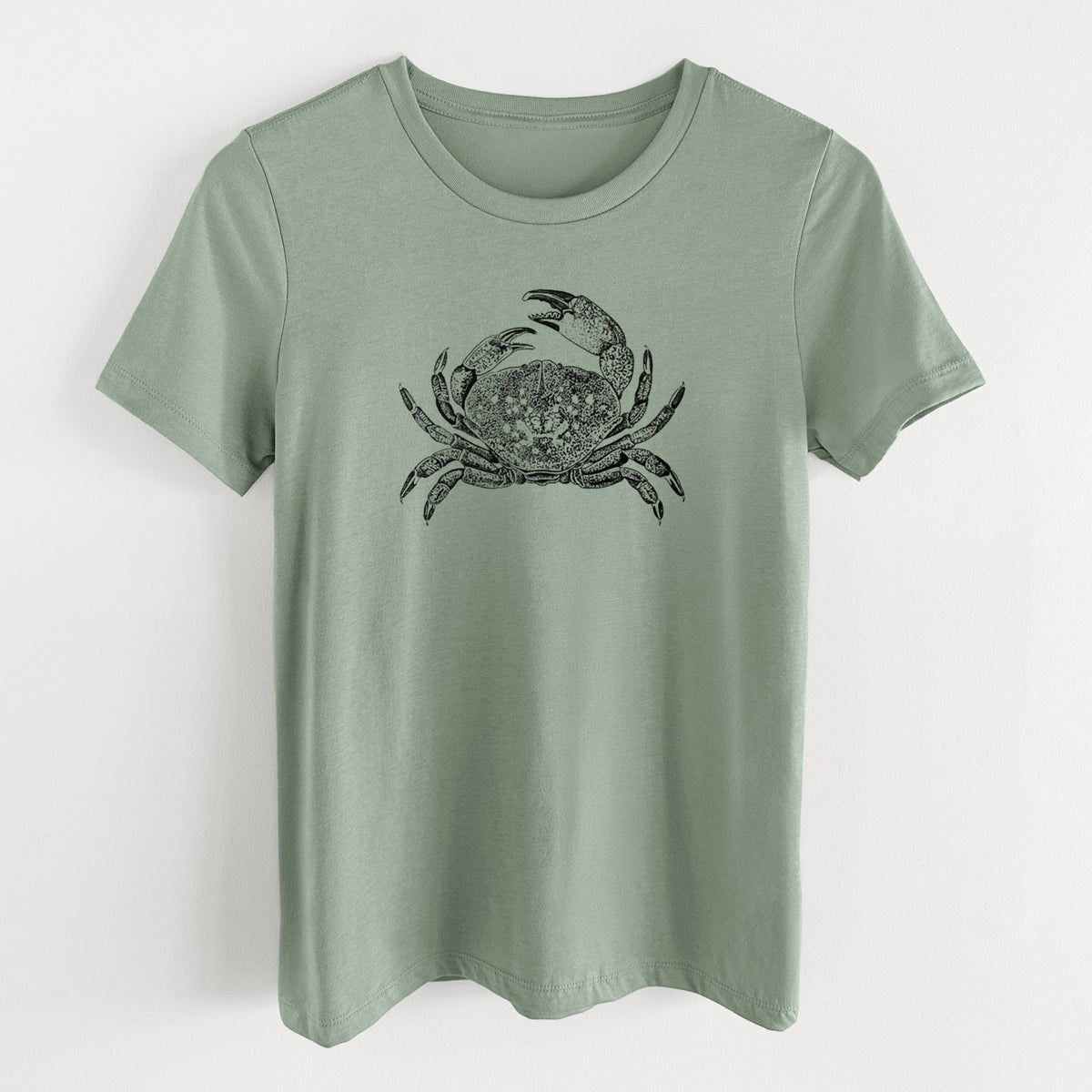 Sage green women's relaxed fit cotton t-shirt laid flat, printed with a detailed black ink illustration of a Dungeness crab with claws raised, seen from above.