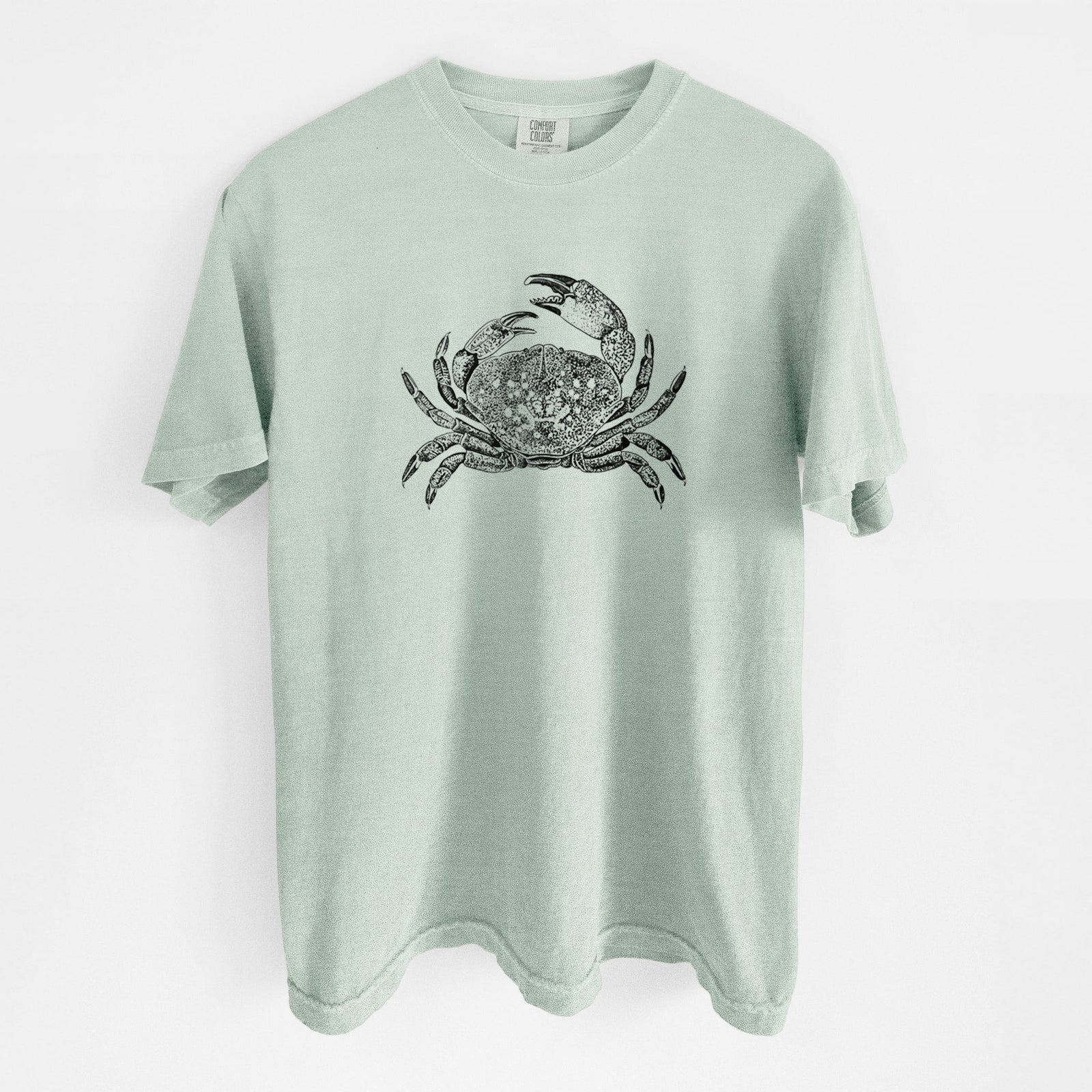 Blue jean Comfort Colors t-shirt laid flat, printed with a detailed black ink illustration of a Dungeness crab with claws raised, seen from above.