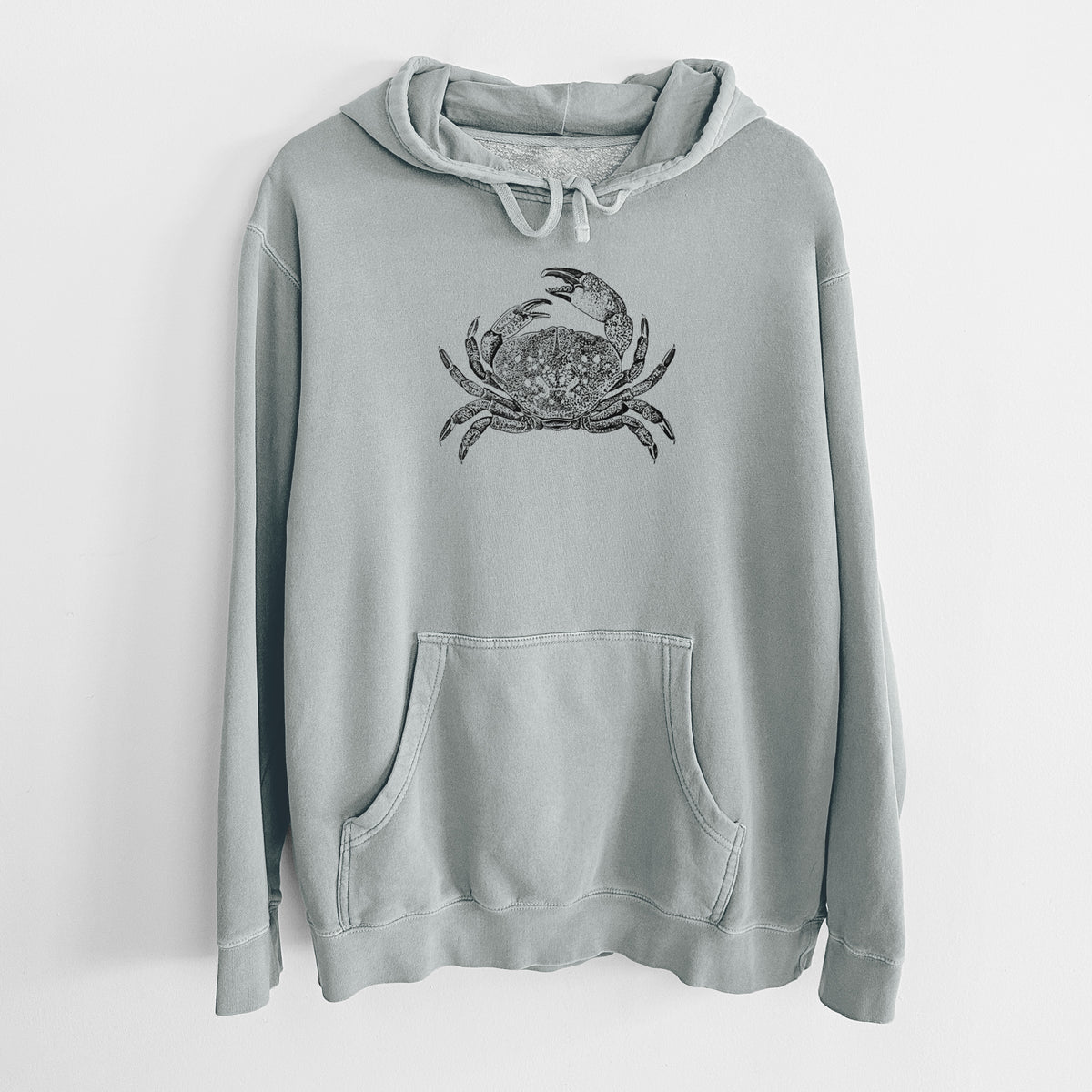 Sage green pigment dyed hoodie laid flat, printed with a detailed black ink illustration of a Dungeness crab with claws raised, seen from above.
