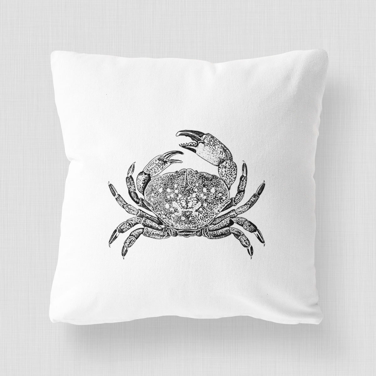White pillow cover printed with a detailed black ink illustration of a Dungeness crab with claws raised, seen from above.