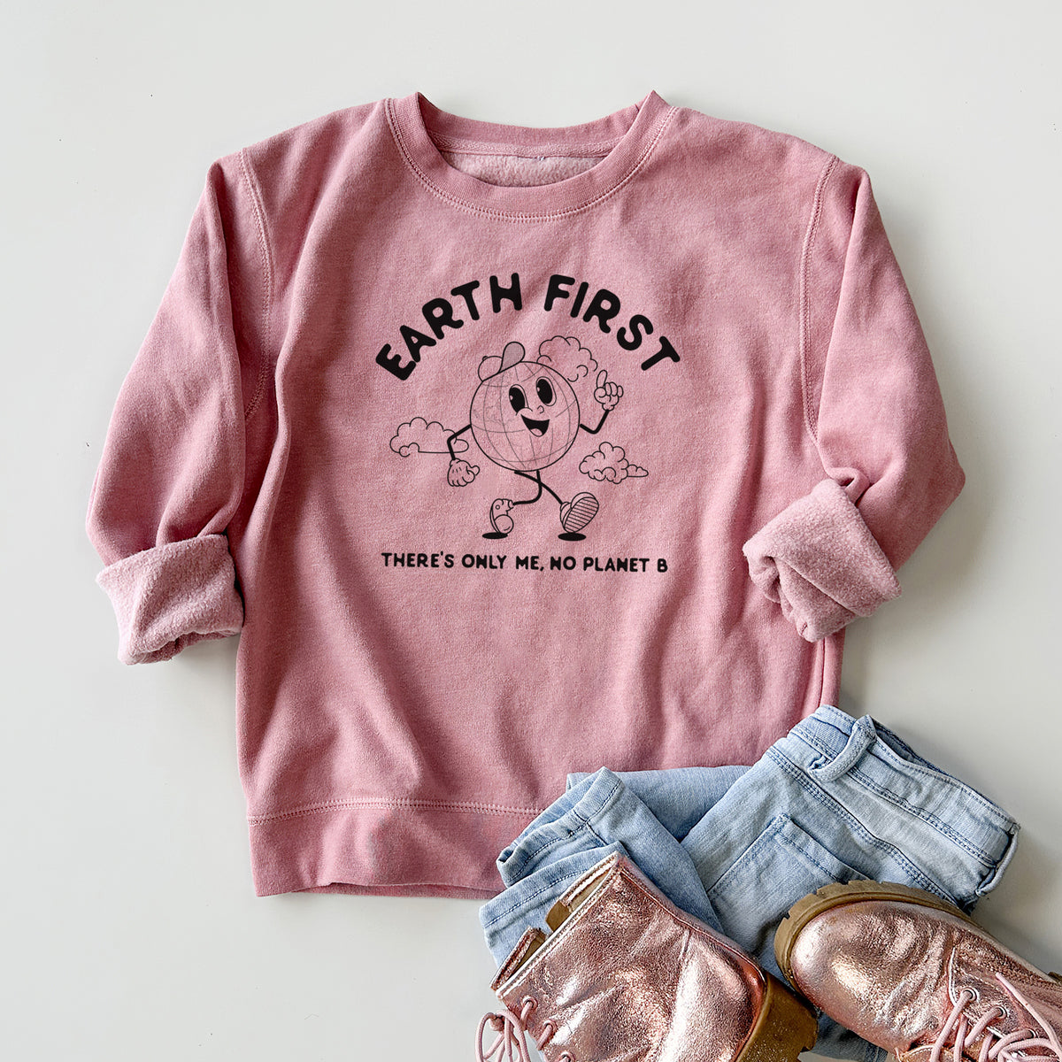 Youth crewneck sweatshirt printed with a cheerful cartoon Earth running, with the words Earth First and There's Only Me, No Planet B, styled flat with jeans and boots.