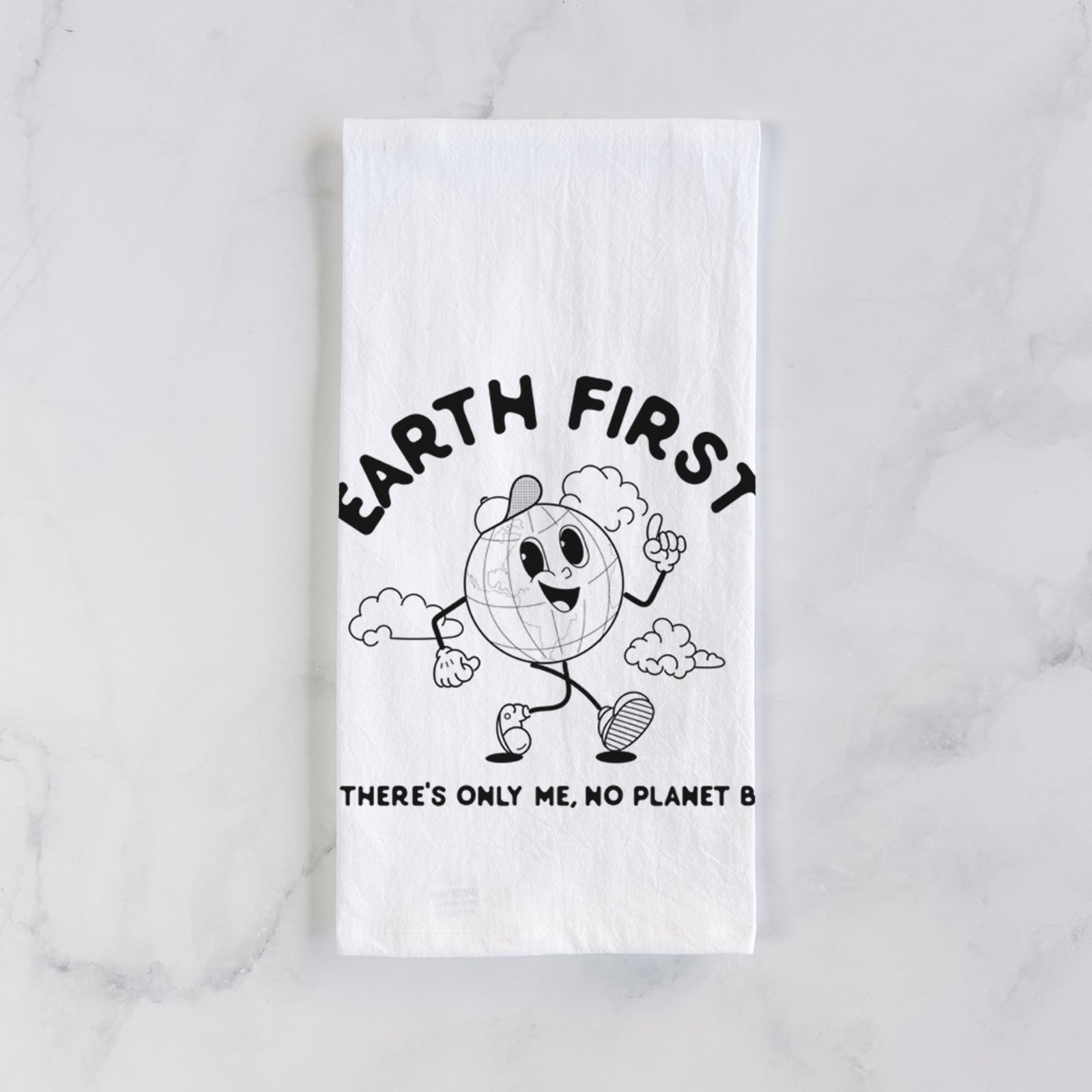White cotton tea towel printed with a cheerful cartoon Earth running, with the words Earth First and There's Only Me, No Planet B, on a marble counter beside a round wooden cutting board and greenery.