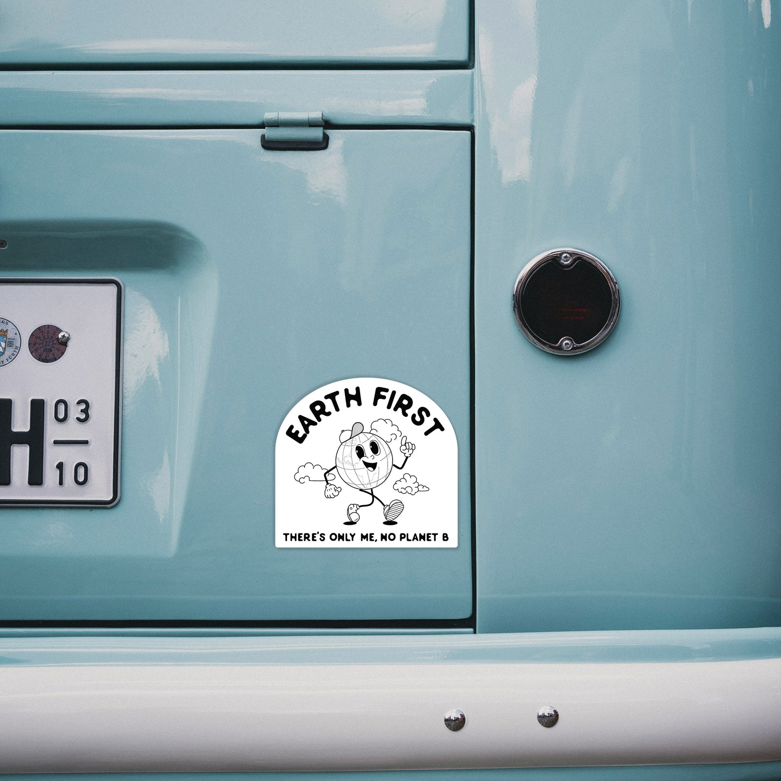 Hand holding a 4 inch vinyl decal of a cheerful cartoon Earth running, with the words Earth First and There's Only Me, No Planet B.