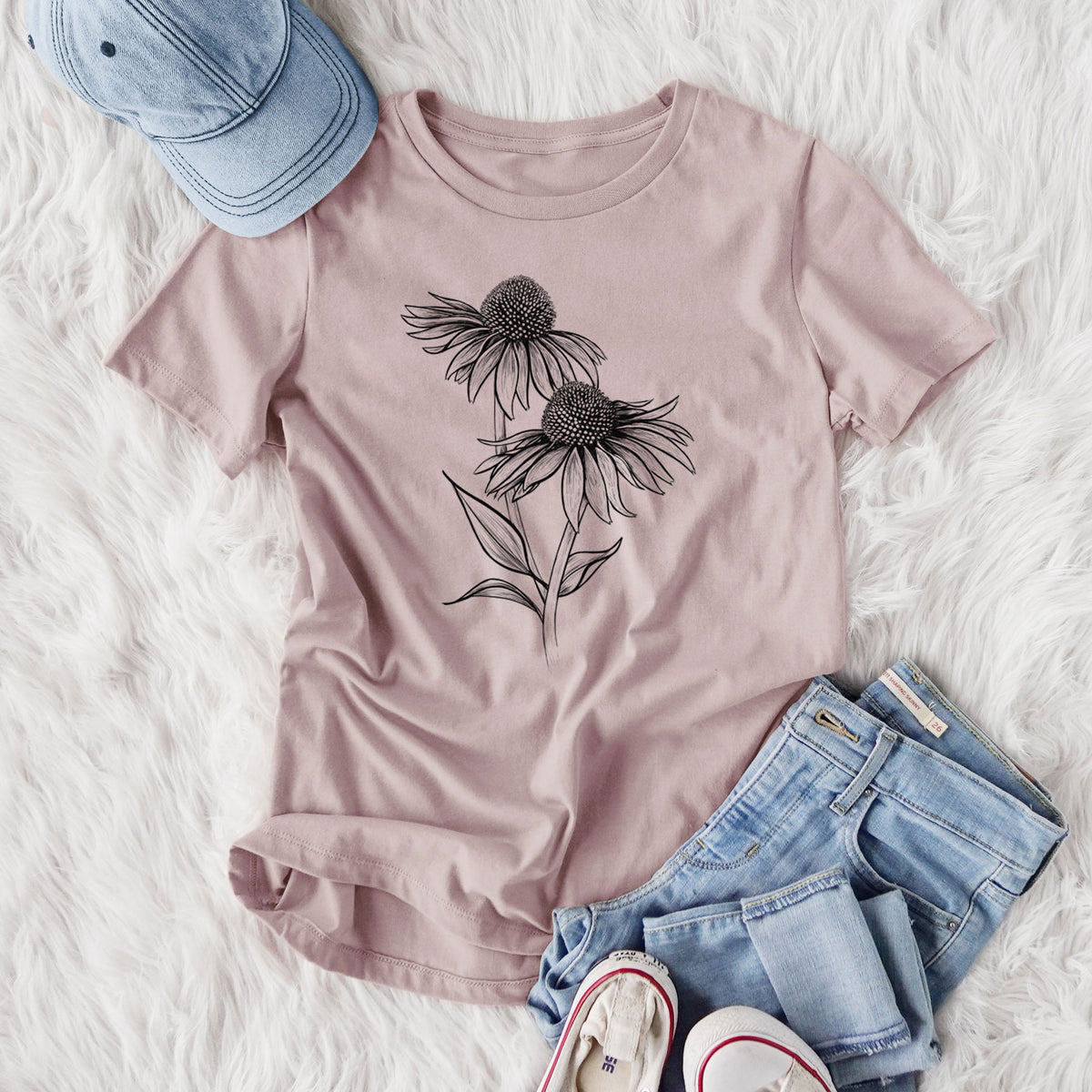 Women's relaxed fit cotton t-shirt printed with a black ink line drawing of two coneflowers on tall stems, styled flat on a white faux fur rug with jeans.