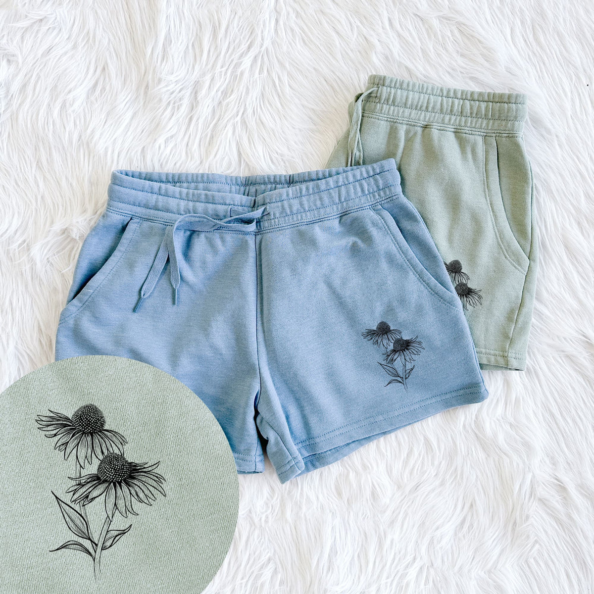 Two pairs of Cali Wave shorts in different colors printed with a black ink line drawing of two coneflowers on tall stems, with a close-up of the print.