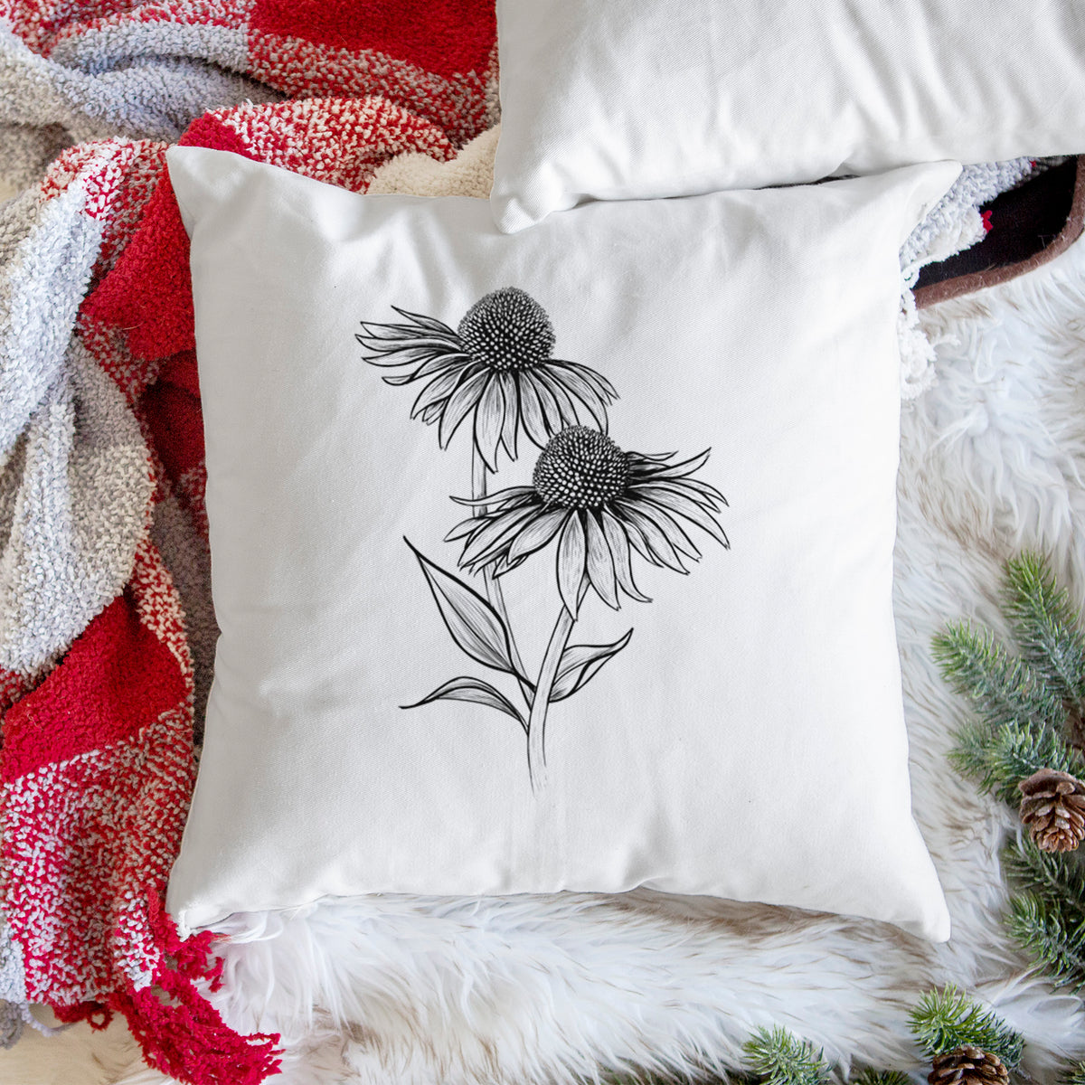 White pillow cover printed with a black ink line drawing of two coneflowers on tall stems, on a woven chair.