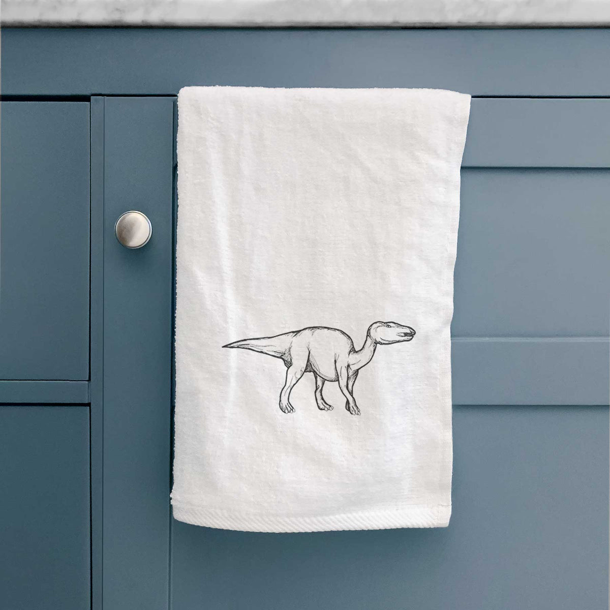 White hand towel printed with a black ink illustration of an Edmontosaurus walking.