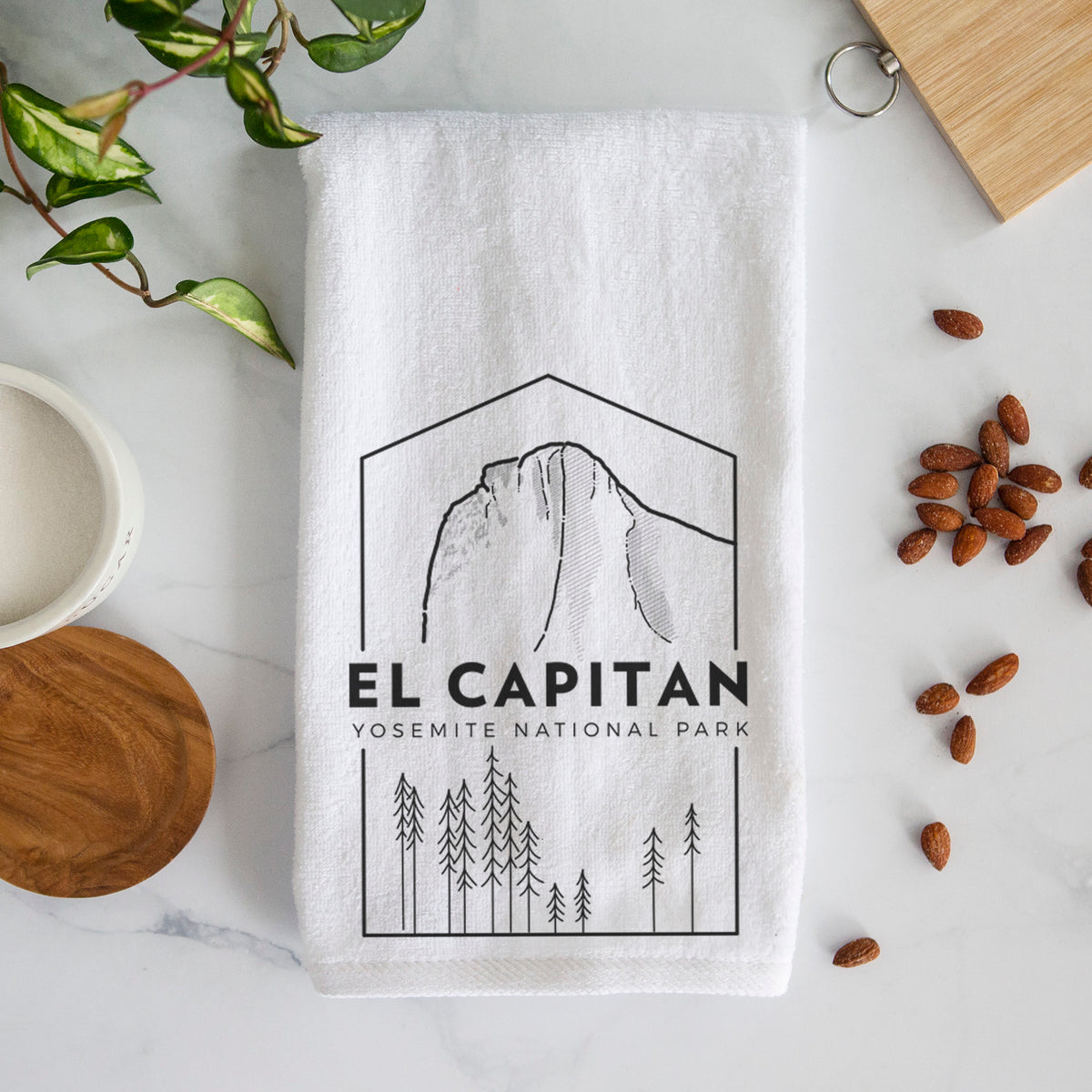 White hand towel printed with a black line art badge of El Capitan rising above a pine forest, with the words El Capitan, Yosemite National Park.