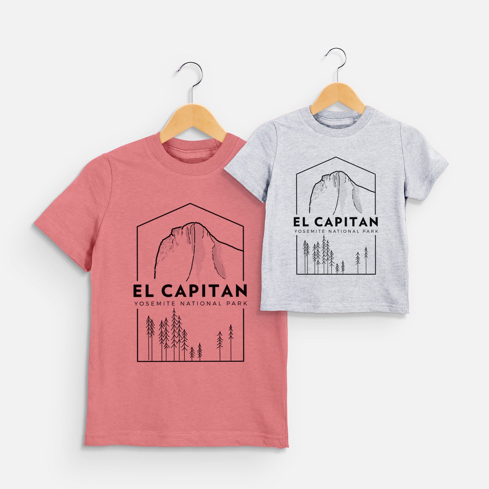 Two youth t-shirts in different colors on hangers, printed with a black line art badge of El Capitan rising above a pine forest, with the words El Capitan, Yosemite National Park.