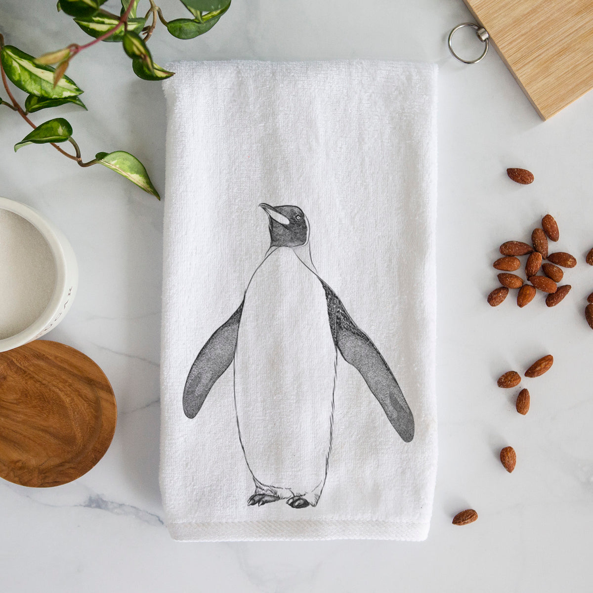 White hand towel printed with a black ink illustration of an emperor penguin standing.