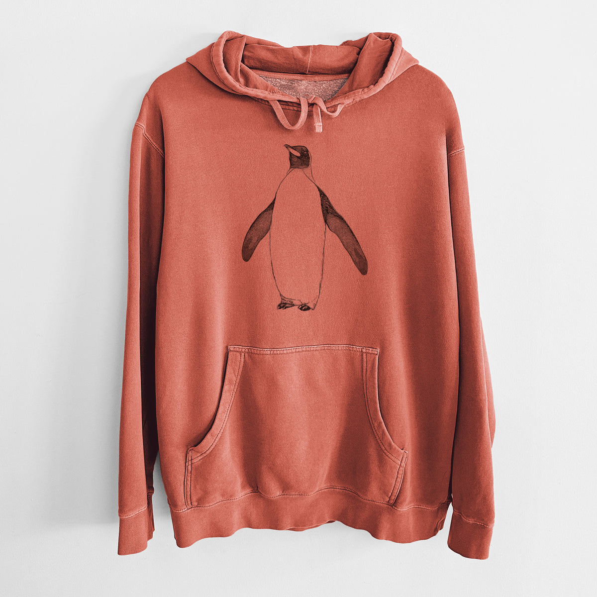 Amber orange pigment dyed hoodie laid flat, printed with a black ink illustration of an emperor penguin standing.