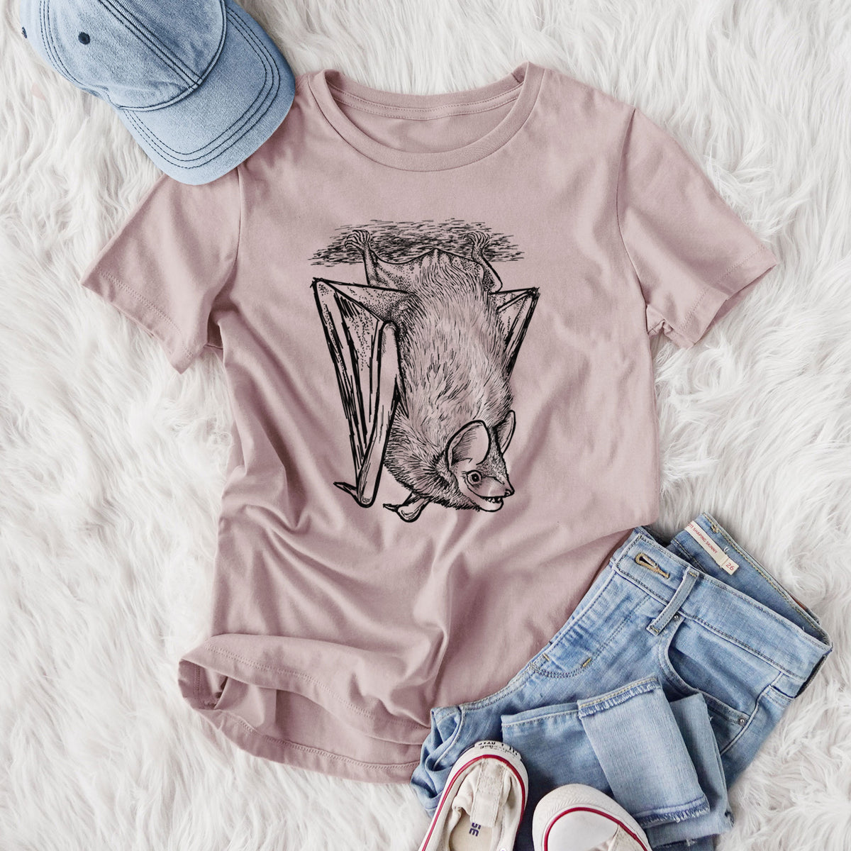 Women's relaxed fit cotton t-shirt printed with a detailed black ink illustration of a big brown bat hanging upside down, styled flat on a white faux fur rug with jeans.