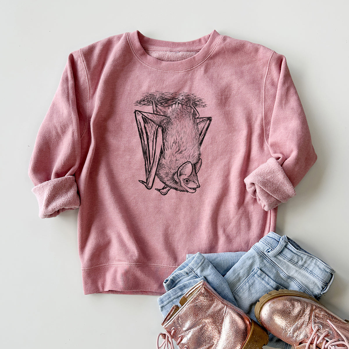 Youth crewneck sweatshirt printed with a detailed black ink illustration of a big brown bat hanging upside down, styled flat with jeans and boots.