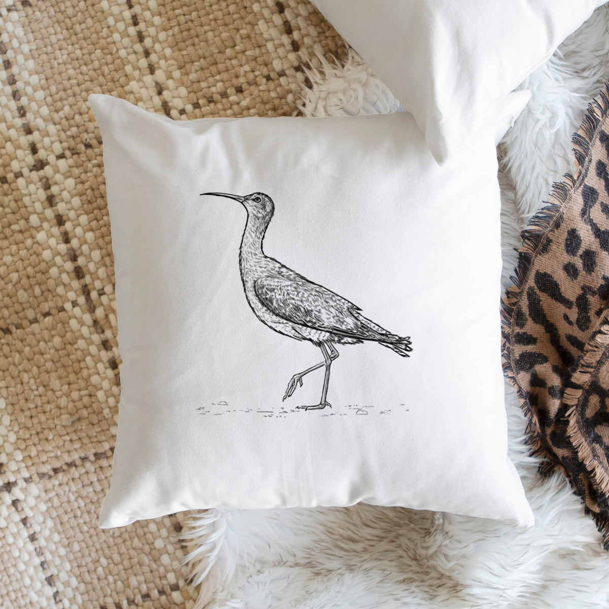 White pillow cover printed with a detailed black ink illustration of an Eskimo curlew with its long curved bill, walking, on a woven chair.