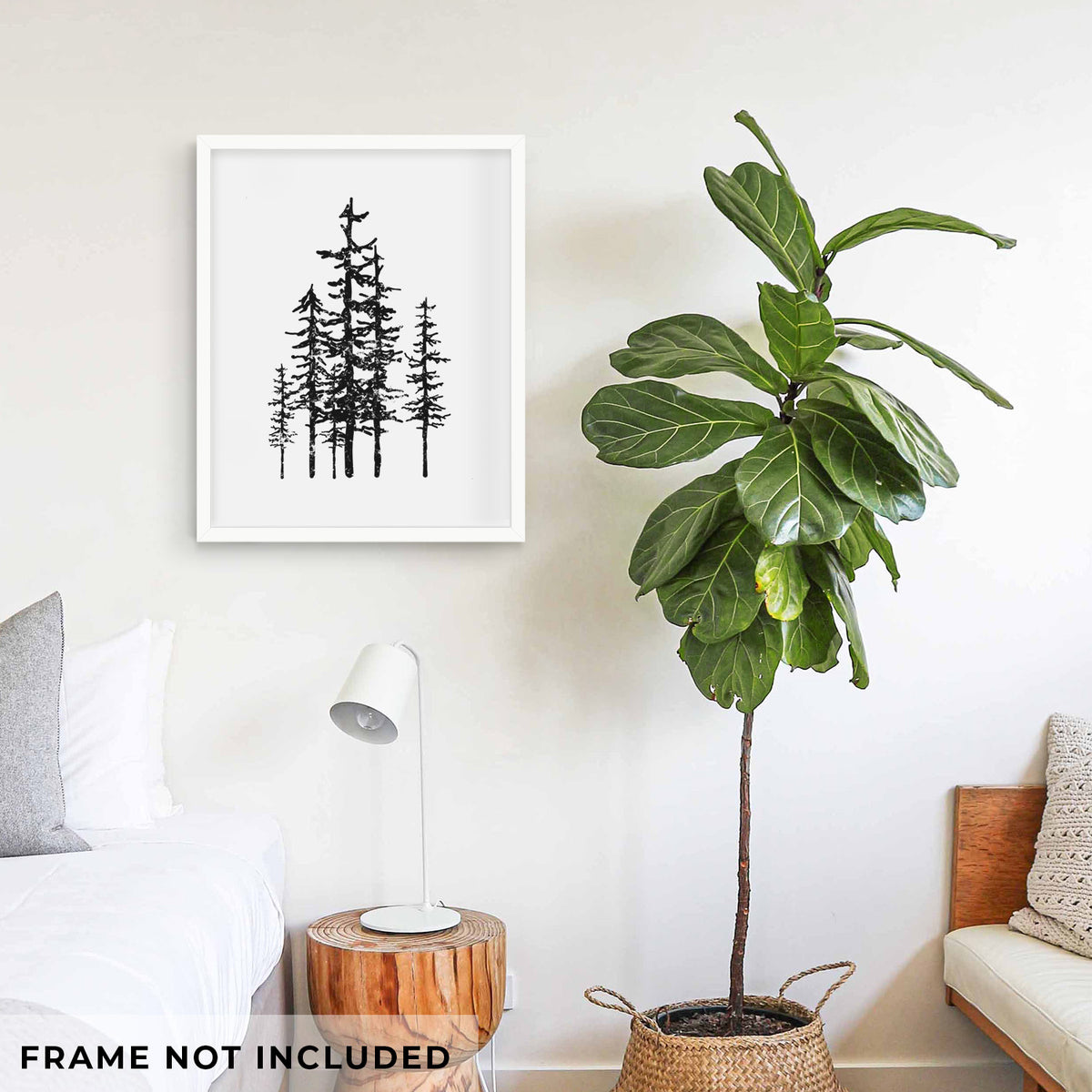 Art print of a black ink illustration of a cluster of evergreen trees of varying heights, shown framed on a living room wall beside a potted plant. Frame not included.
