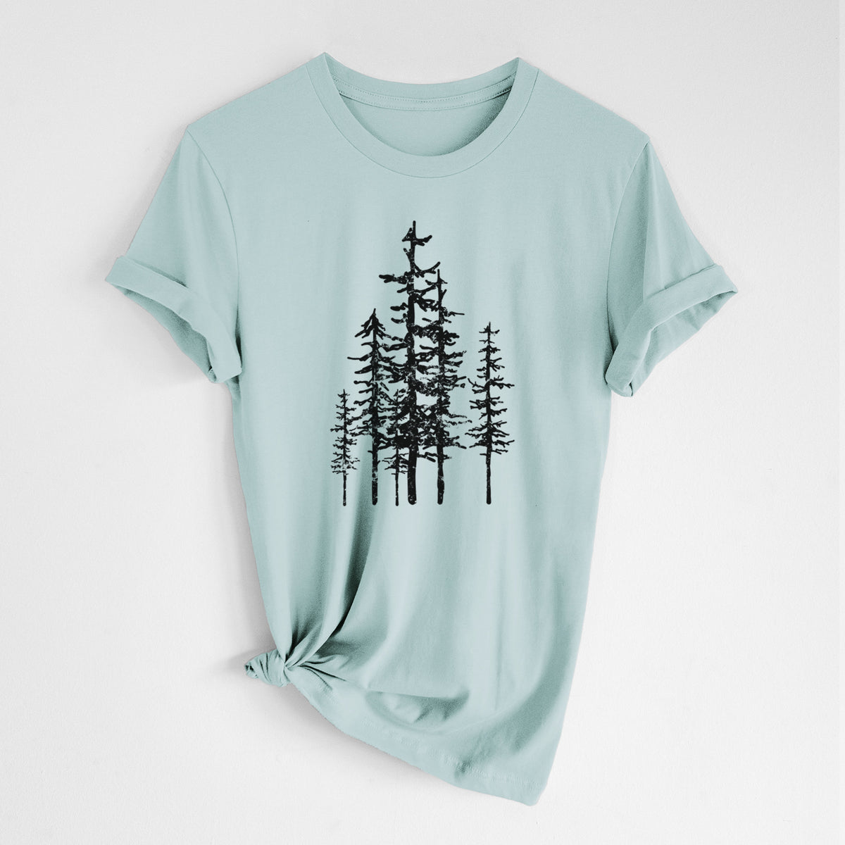 Dusty blue lightweight cotton t-shirt laid flat with the sleeves rolled, printed with a black ink illustration of a cluster of evergreen trees of varying heights.