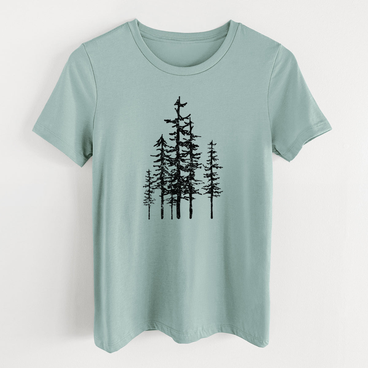 Dusty blue women's relaxed fit cotton t-shirt laid flat, printed with a black ink illustration of a cluster of evergreen trees of varying heights.