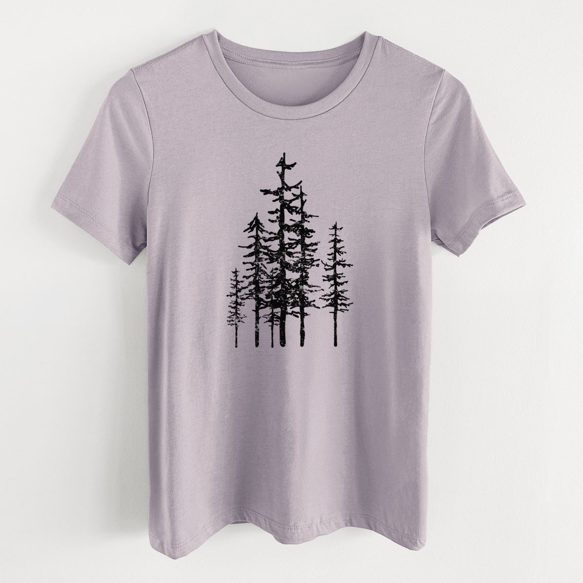 Light violet women's relaxed fit cotton t-shirt laid flat, printed with a black ink illustration of a cluster of evergreen trees of varying heights.