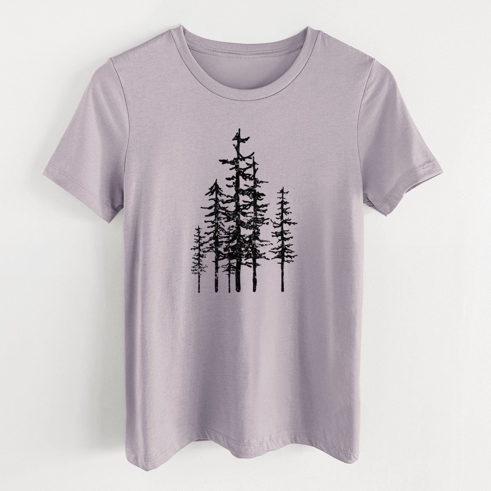 Light violet women's relaxed fit cotton t-shirt laid flat, printed with a black ink illustration of a cluster of evergreen trees of varying heights.