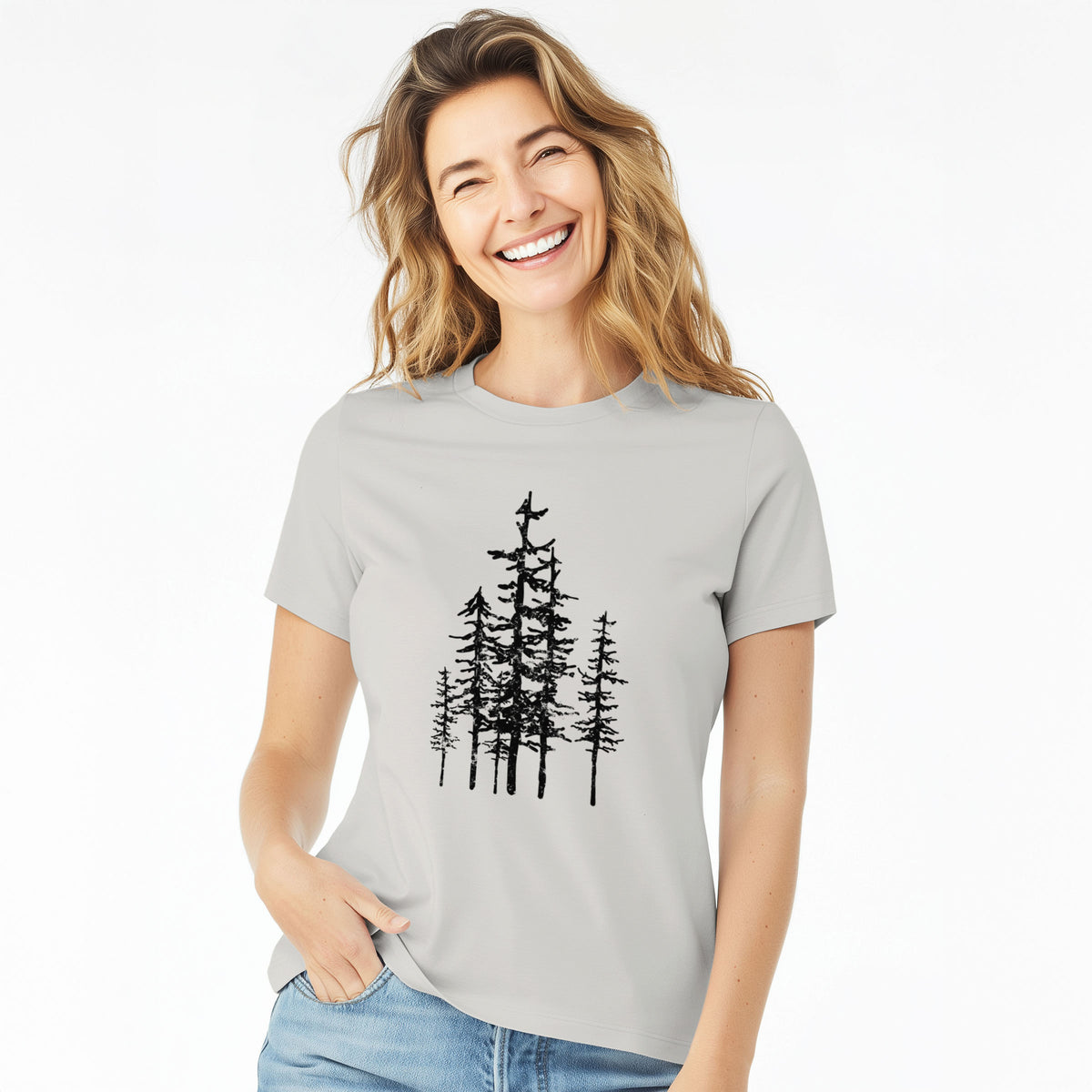 Woman wearing a lunar grey women's relaxed fit cotton t-shirt printed with a black ink illustration of a cluster of evergreen trees of varying heights.
